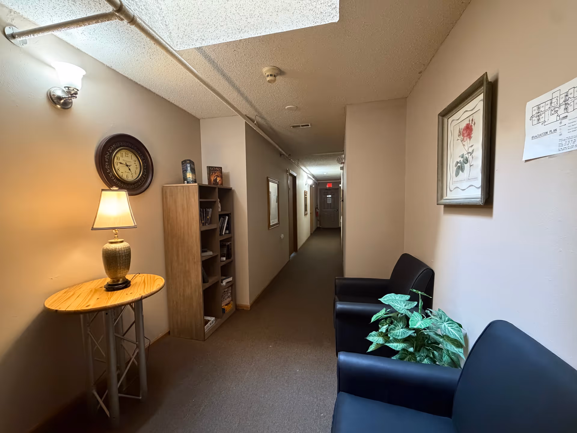 Interior hallway of Bristol Manor - Pacific with seating, plant, clock, and bookshelf.