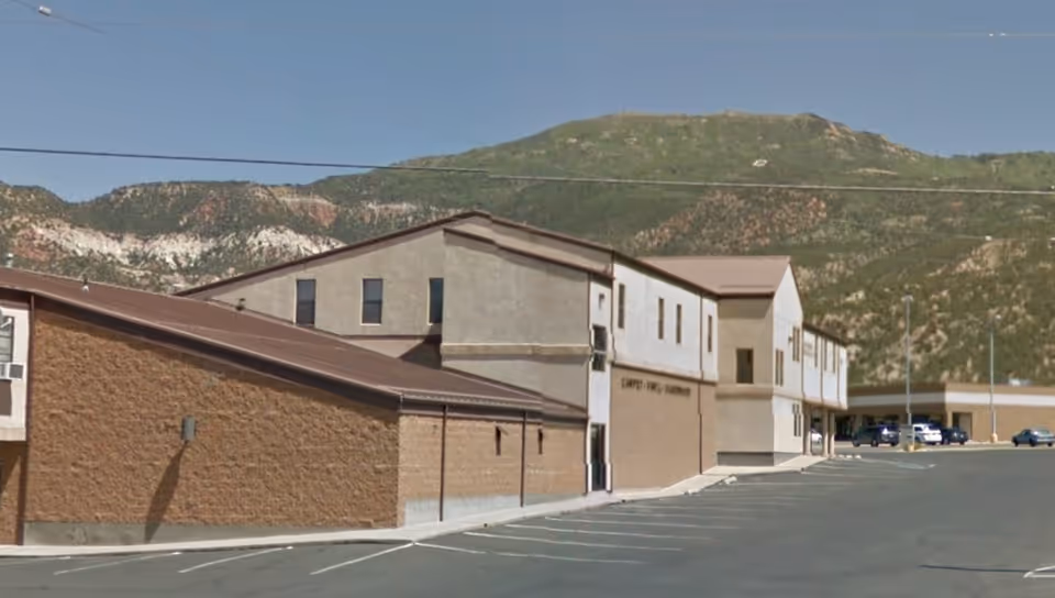Exterior view of Iron County Home Health Agency building with a parking lot and mountains.