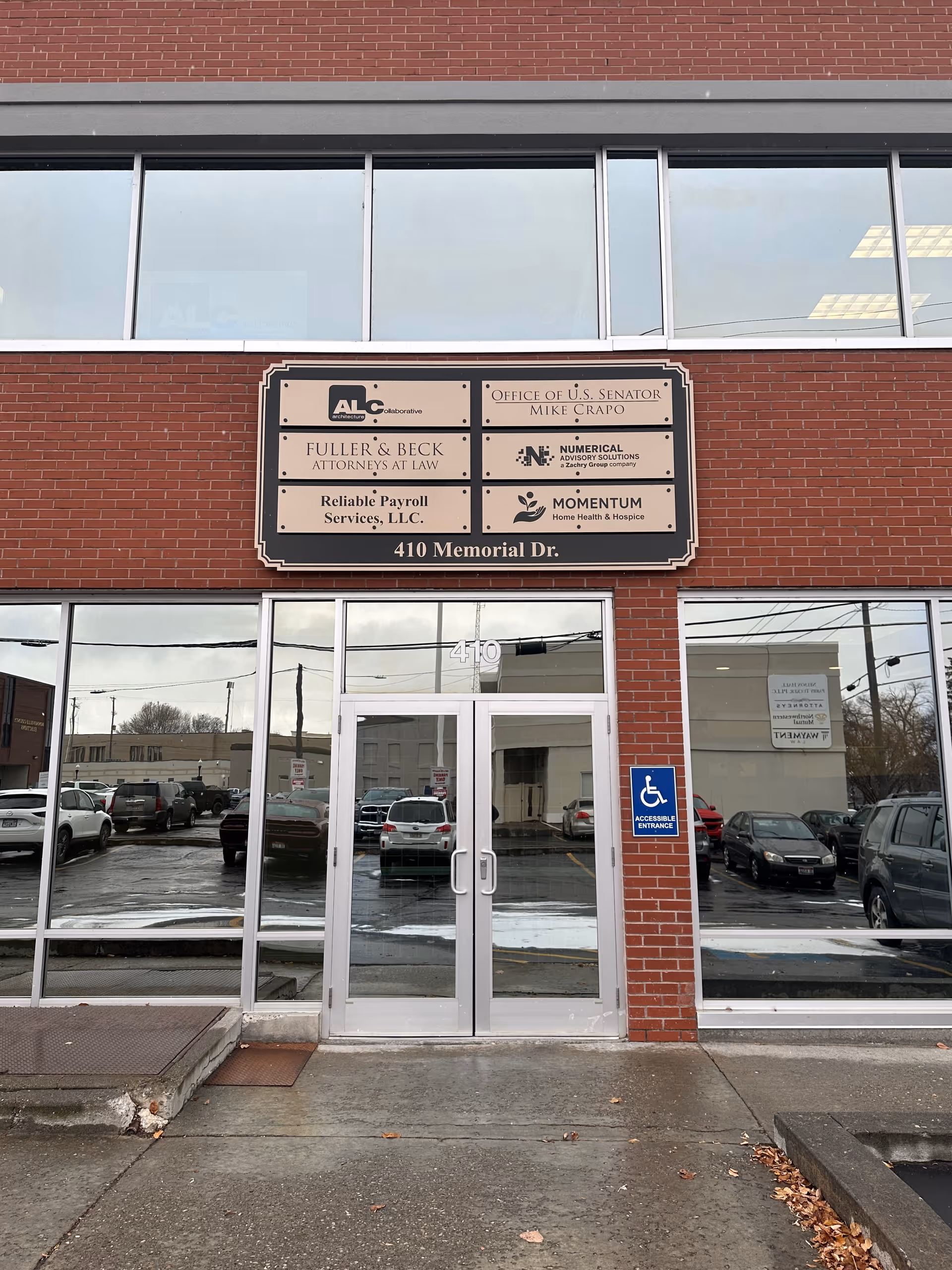 Red brick storefront with glass doors and a Momentum Home Health & Hospice sign.