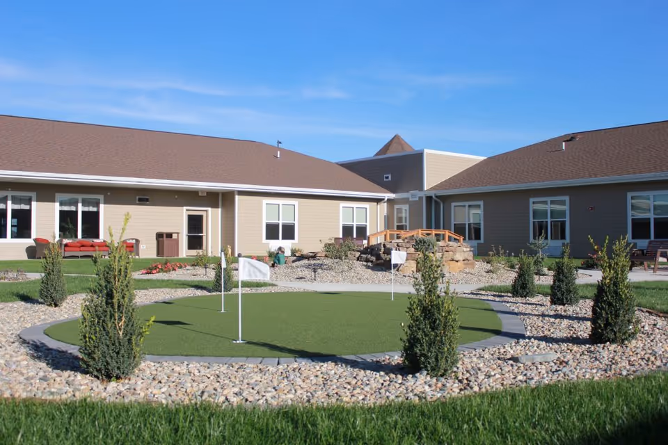 Exterior view of Oak Hill senior living courtyard with a circular putting green and landscaping.
