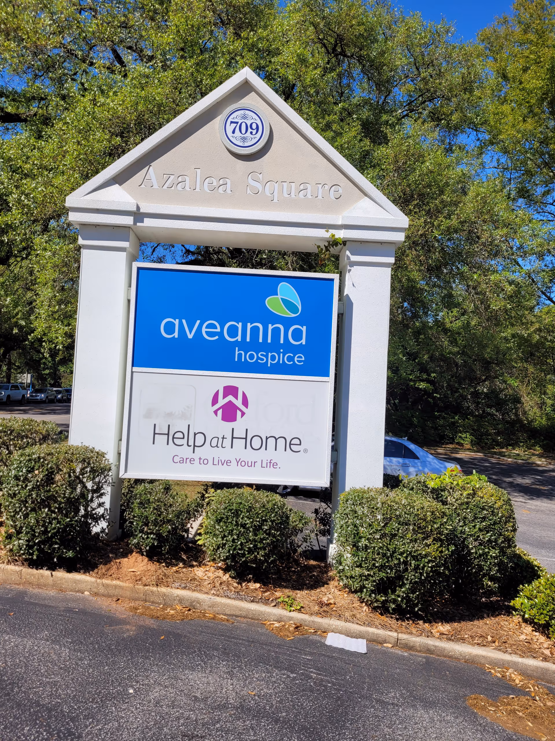 Outdoor sign structure for Aveanna Hospice at Azalea Square with landscaping.
