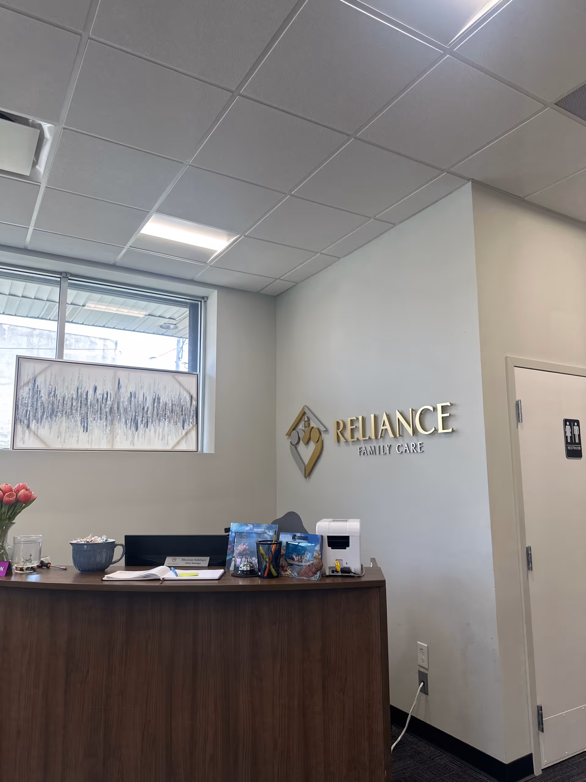 Reception desk inside Reliance Family Care facility with wall signage.