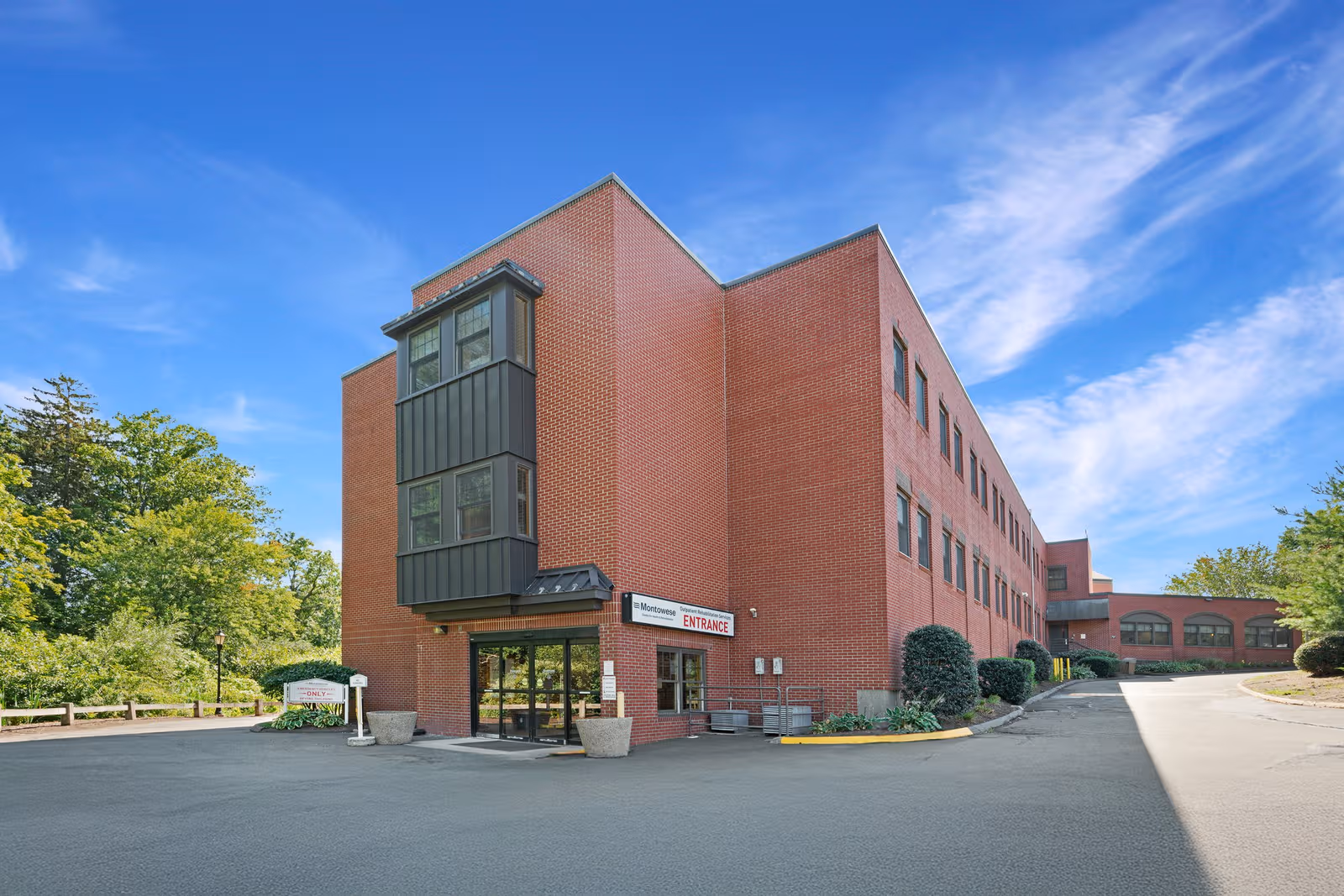 Brick multi-story building with entrance sign labeled Montowese Center, under a clear blue sky.