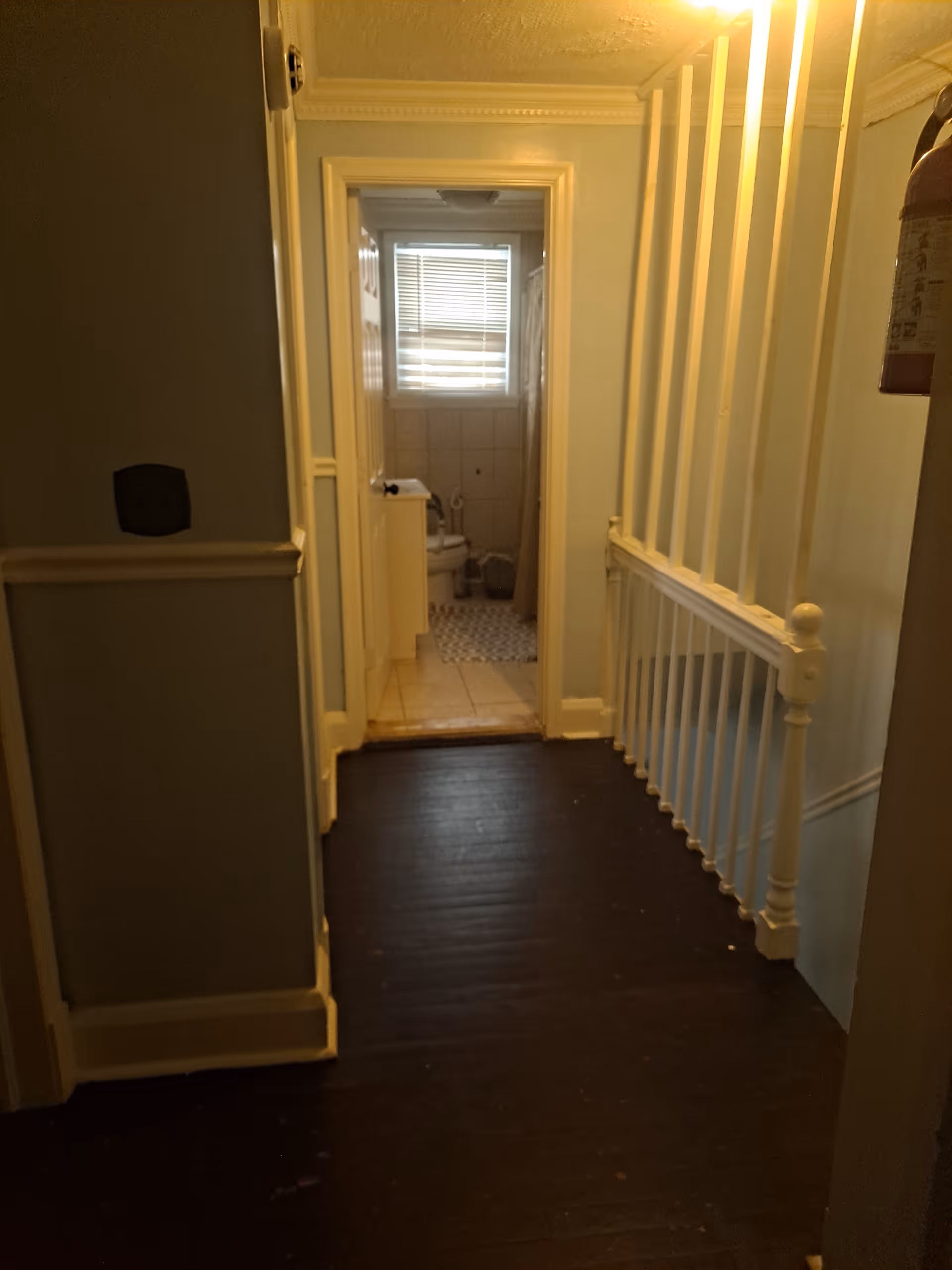 Dim hallway in Shades Place Assisted Living with a doorway leading to a small bathroom.
