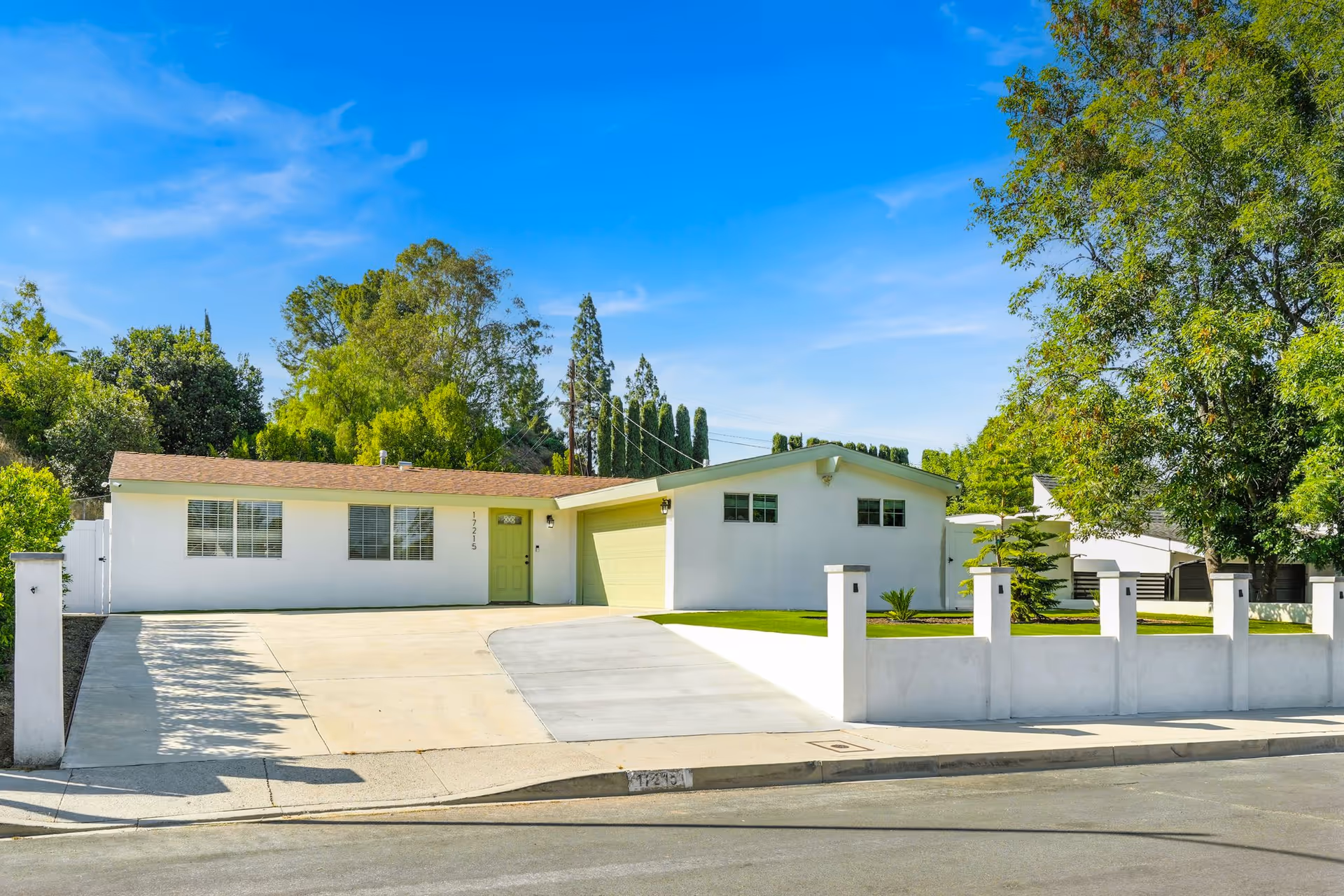 White, single-story assisted living building with a green front door and front lawn.