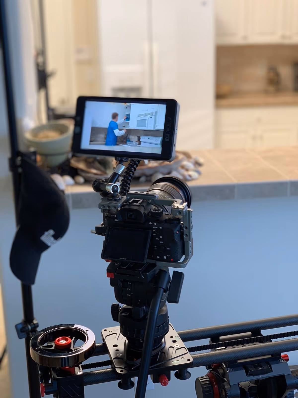 Professional camera rig with monitor filming inside a modern kitchen interior.