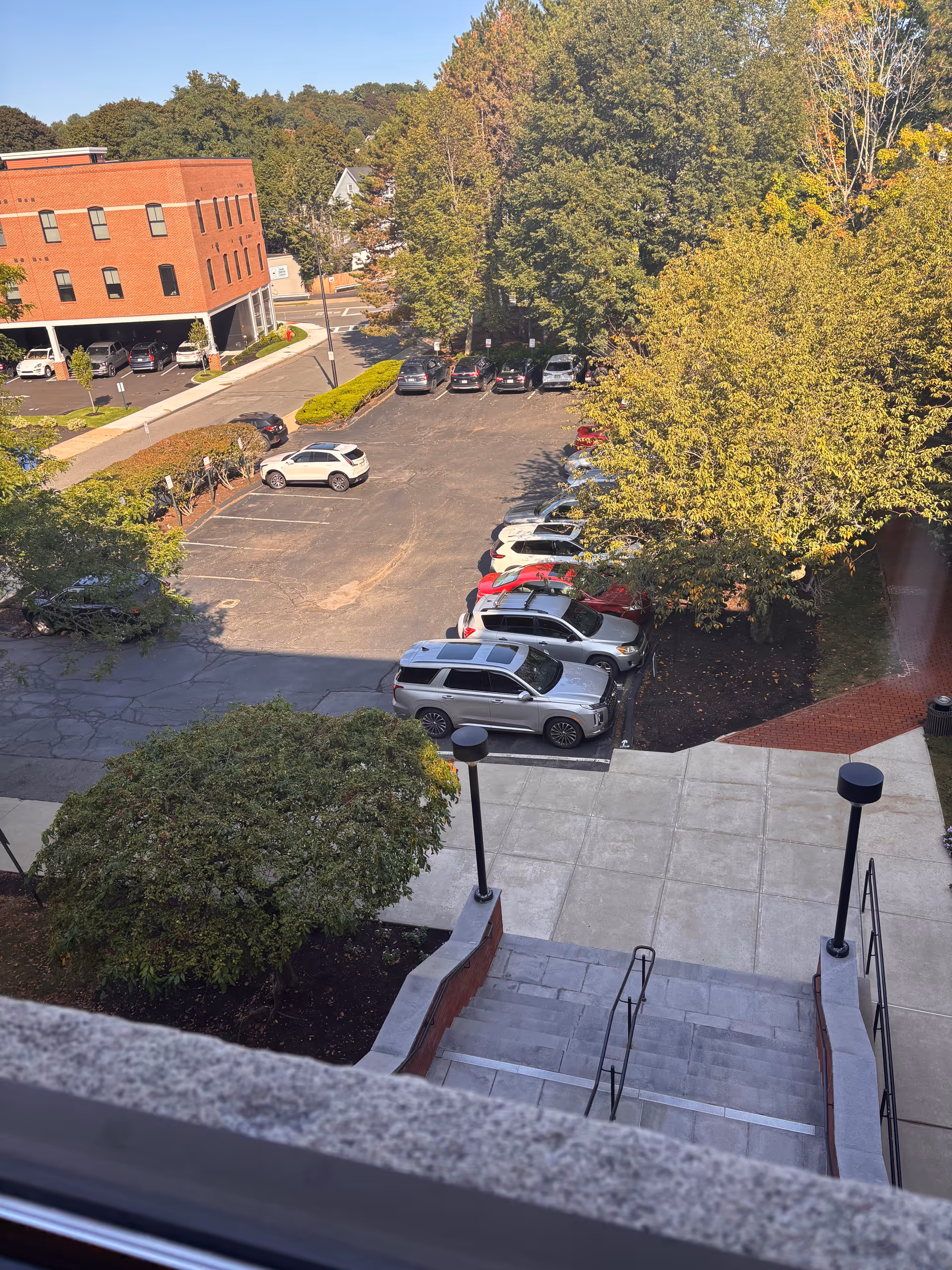 Aerial view of a brick building exterior with a parking lot and surrounding trees.