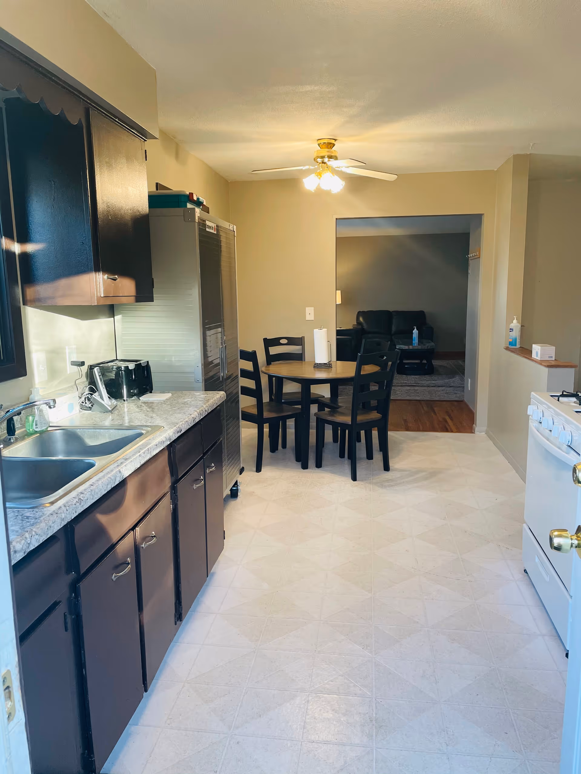 Interior kitchen with dark cabinets, sink, stove, refrigerator, and round dining table.