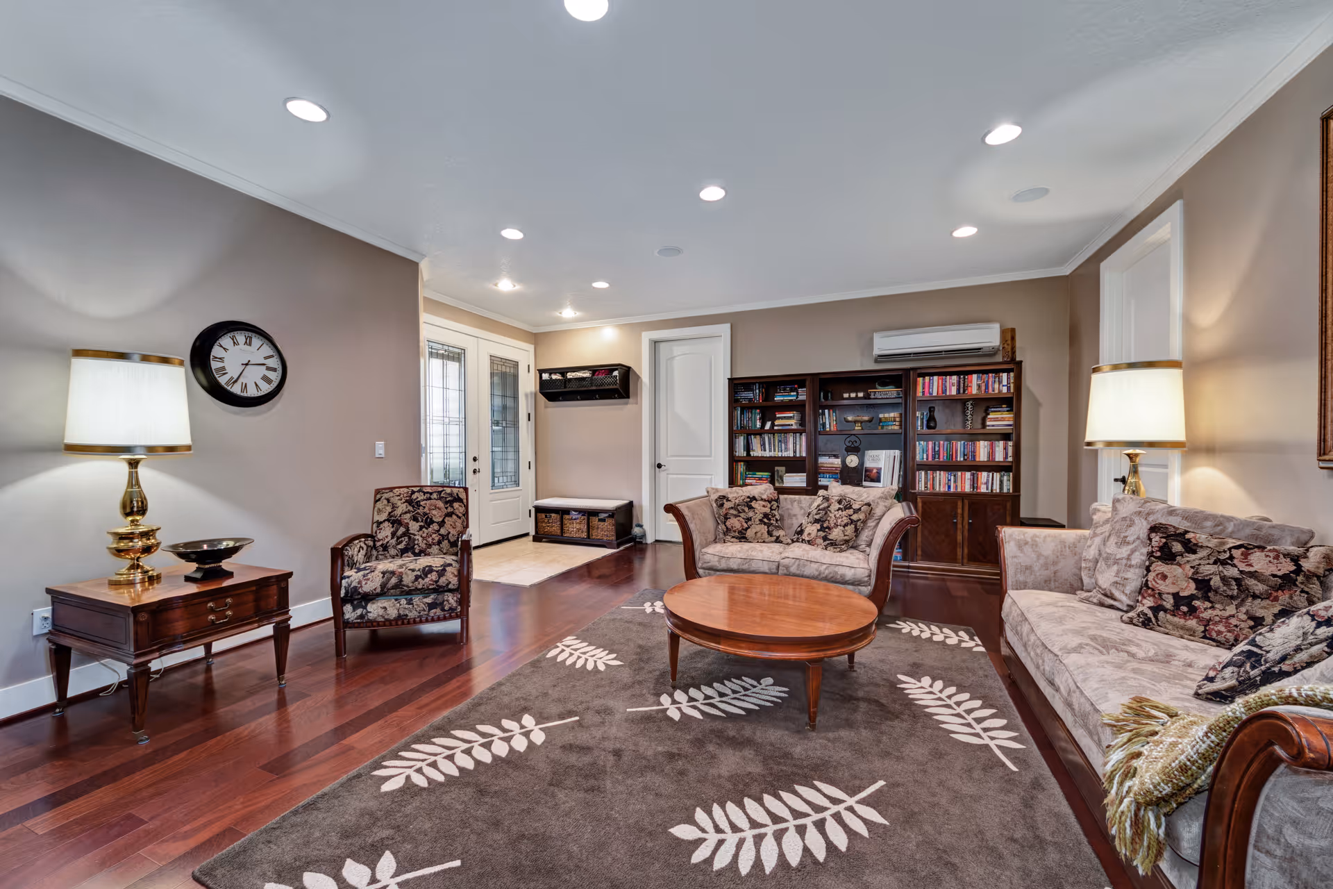 Interior living room with couches, chairs, coffee table, bookshelves, and lamps.
