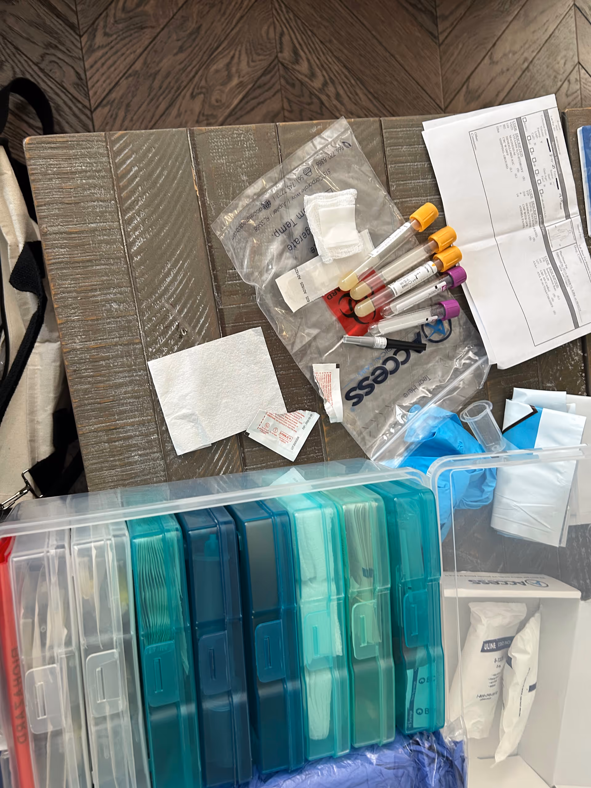 Medical vials and blood collection tubes organized on a wooden lab table.