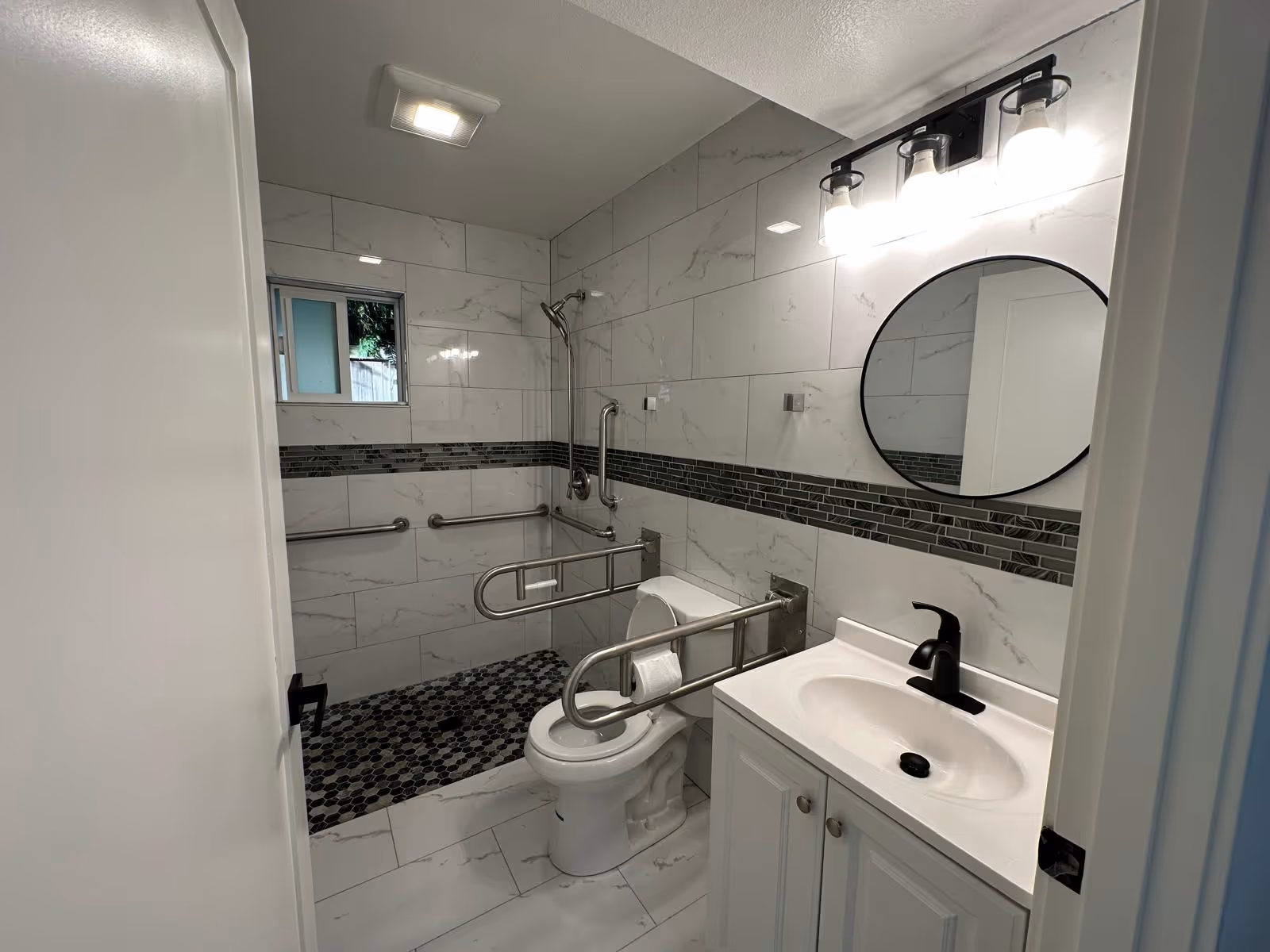 Accessible bathroom with grab bars, tiled walls, sink, mirror, toilet, and shower area.