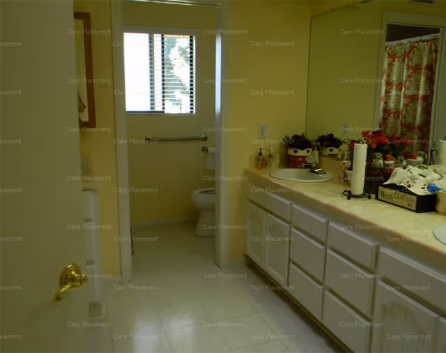 Indoor bathroom with vanity, sink, toiletries, and a separate toilet area.