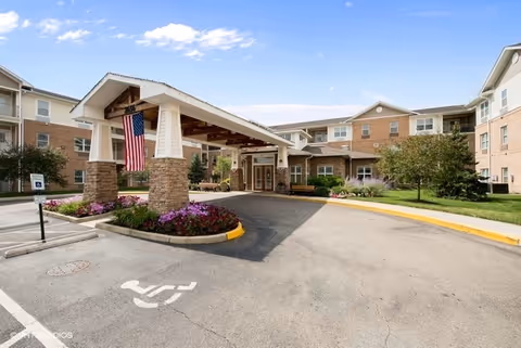 Exterior view of The Wellington at Dayton entrance with a covered driveway and landscaping.