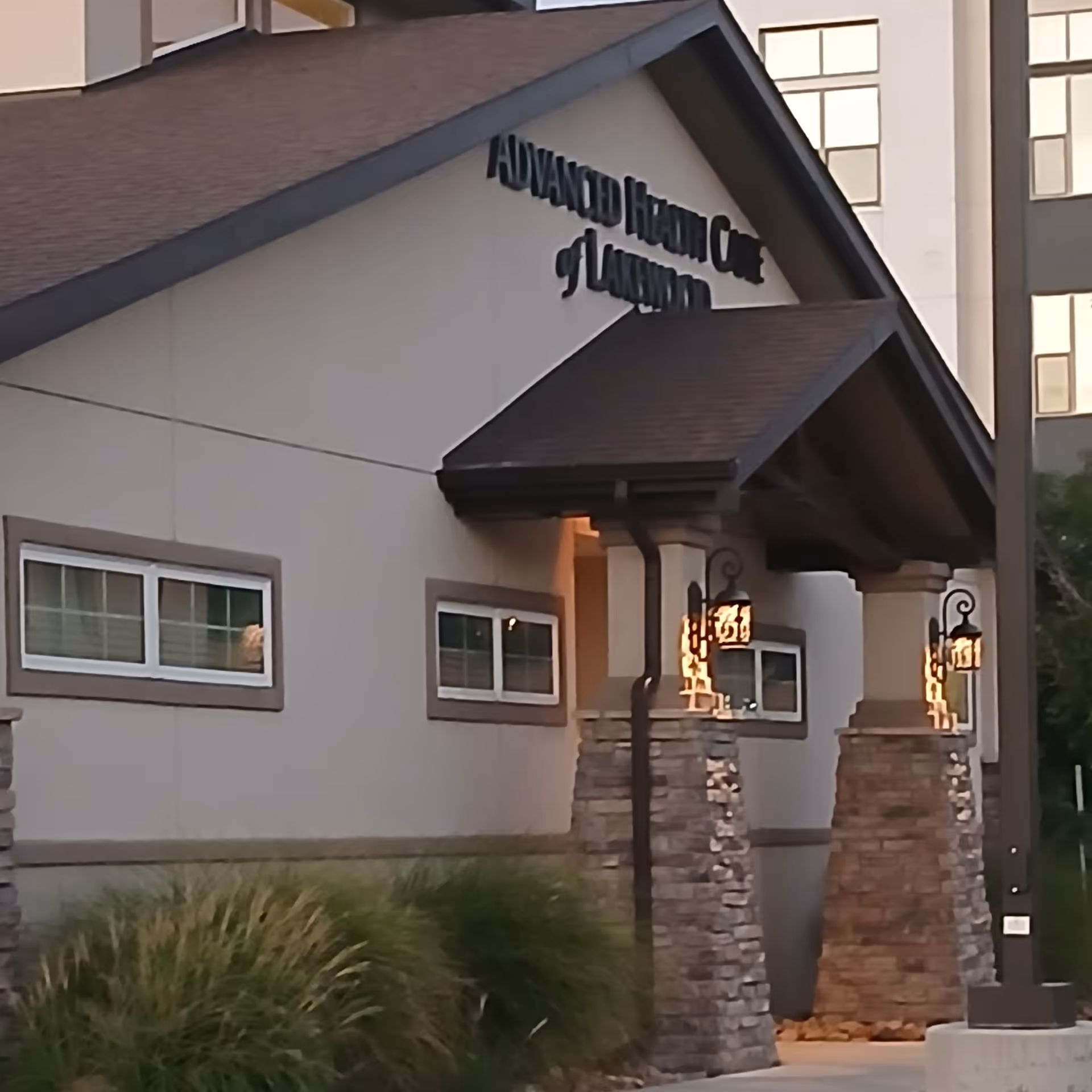 Exterior view of Advanced Health Care of Lakewood entrance with stone columns and lamps