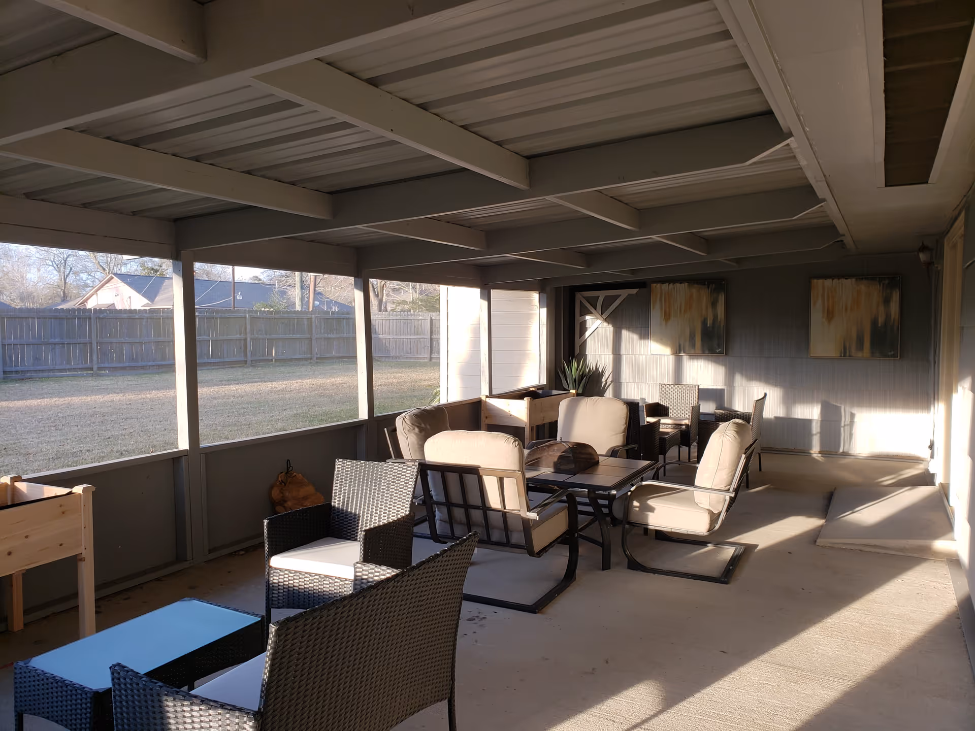 Covered outdoor patio with seating area, glass-top table, and lounge chairs.