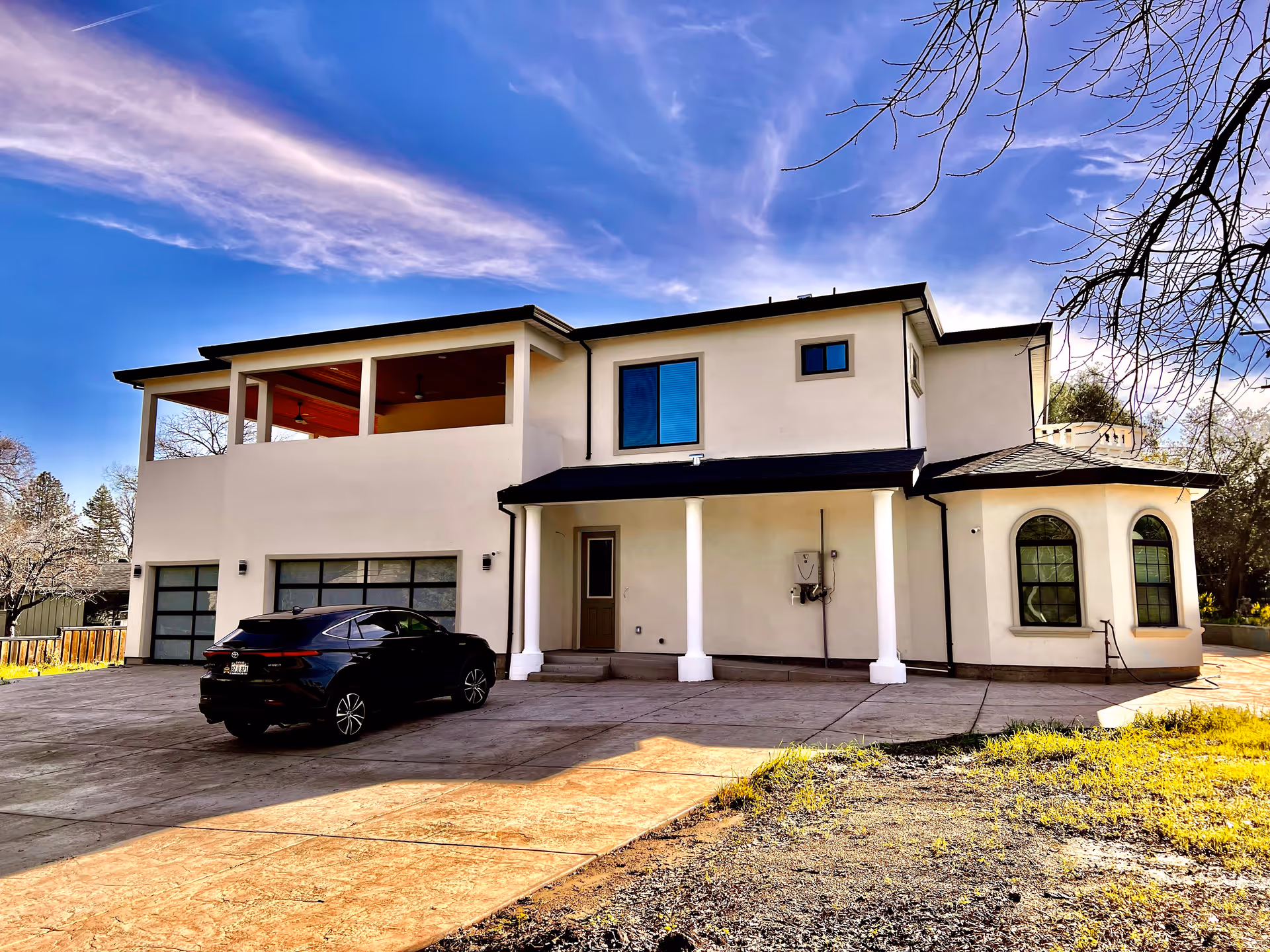 Two-story modern care facility with a driveway, parked car, and clear blue sky.