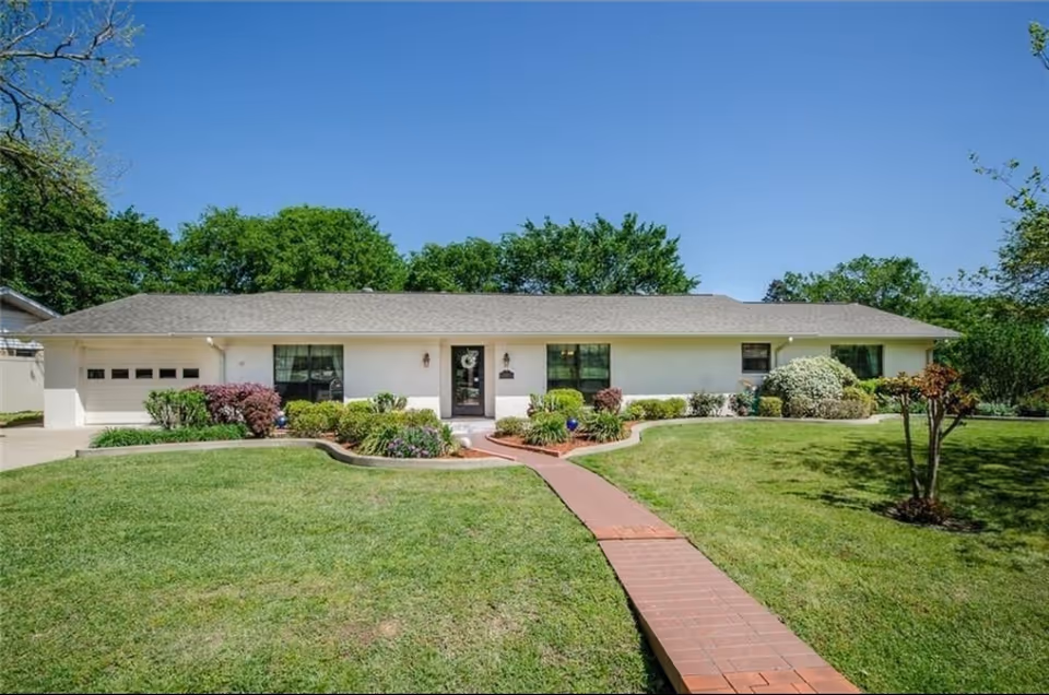 Single-story Kare-inn facility building with a brick walkway, manicured lawn, and shrubs in front.