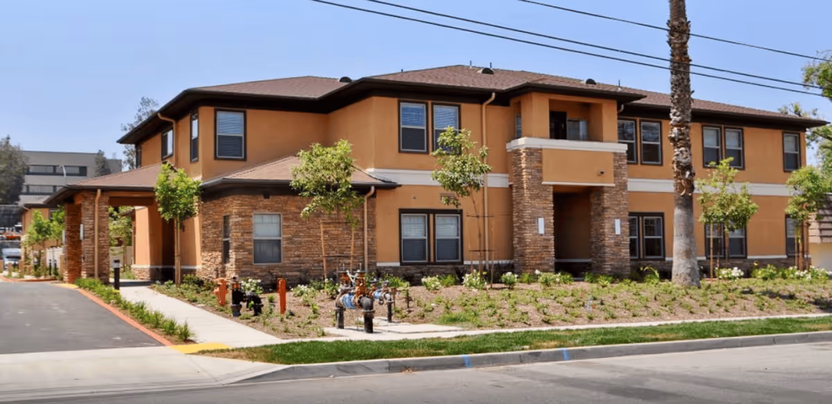 Two-story tan assisted living facility with stone accents and landscaped front yard.