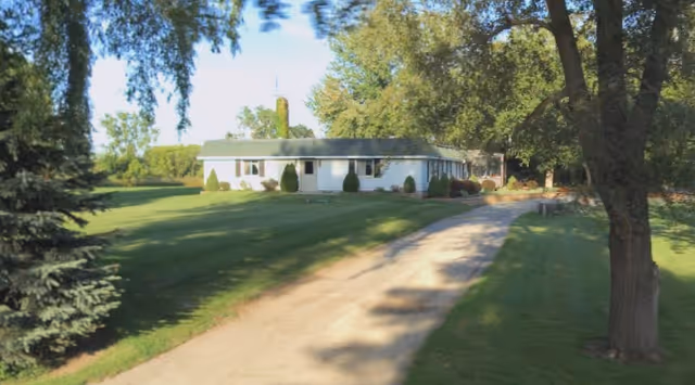 Exterior view of a single-story facility with a gravel driveway and manicured lawn.