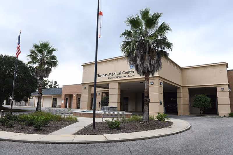 Exterior view of a medical center with palm trees and a curved driveway