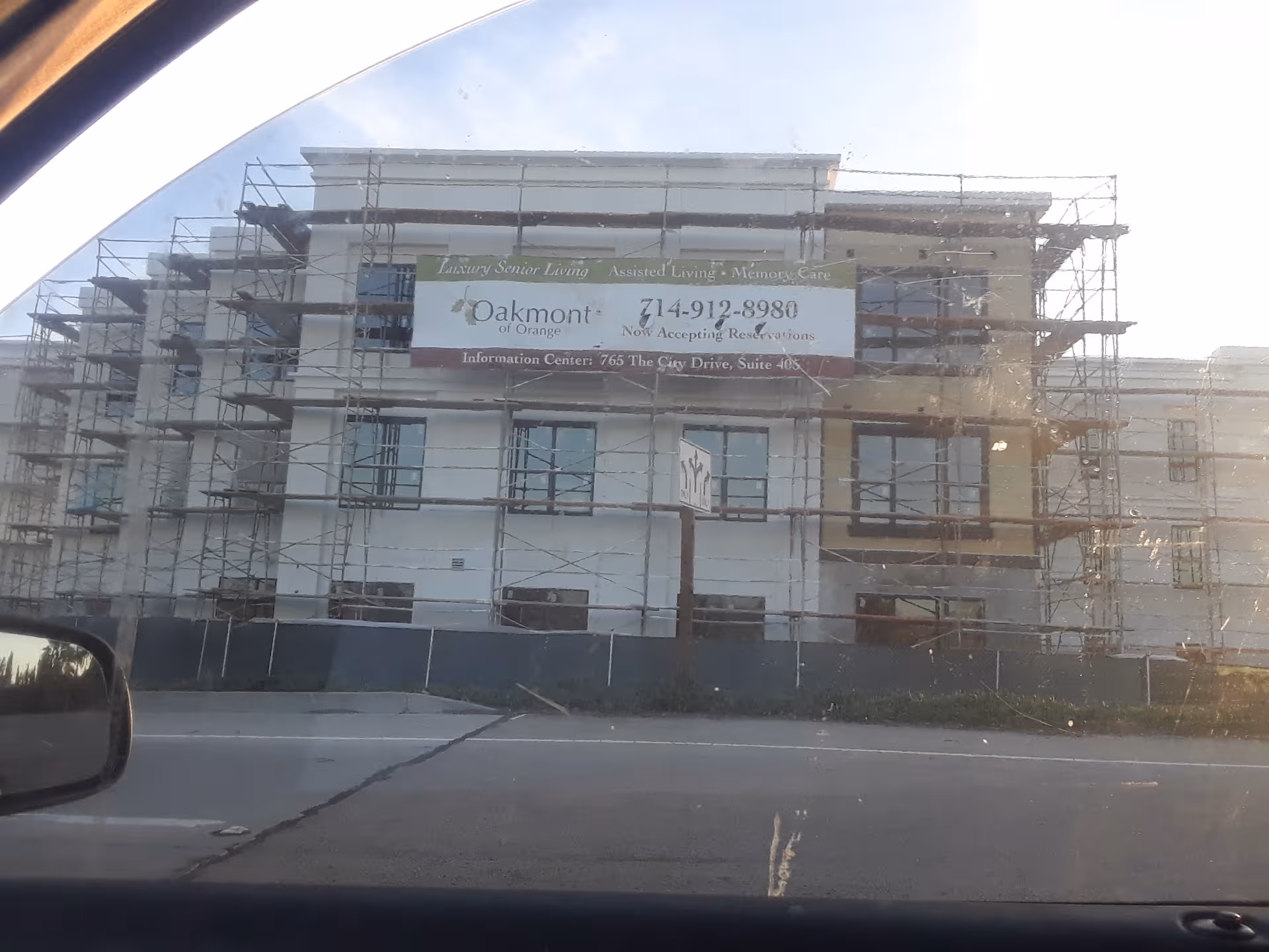 A multi-story building under construction with scaffolding and a banner for Oakmont of Orange.