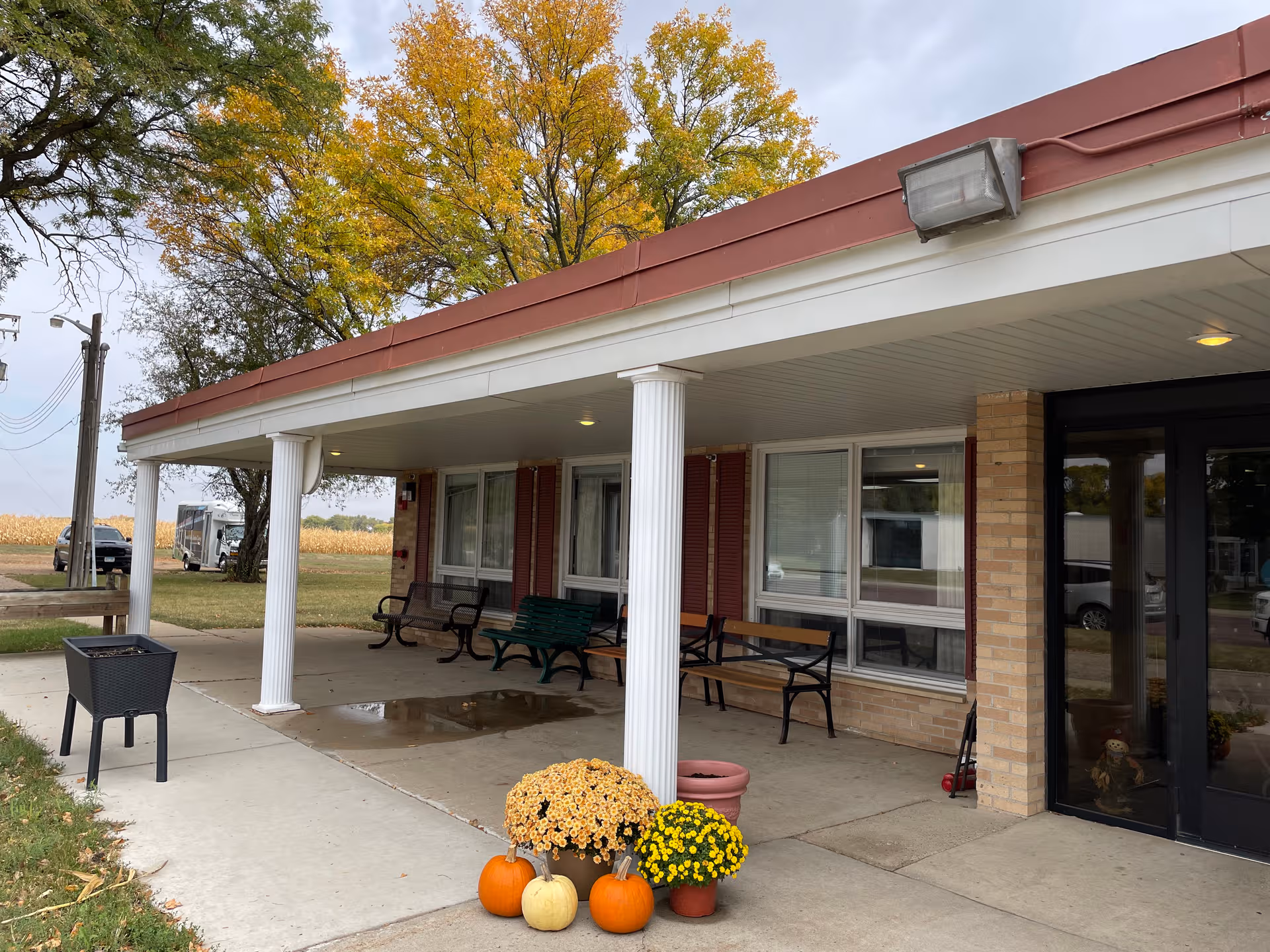 Front entrance of Prairie View Senior Living with benches and fall decorations under a covered walkway.