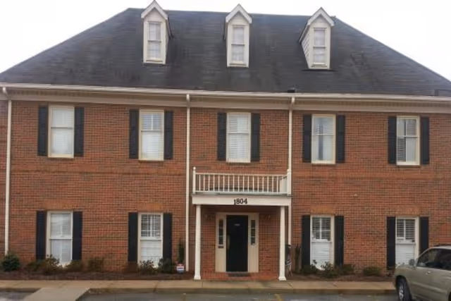 Brick two-story senior living facility front with black shutters and a central entry.