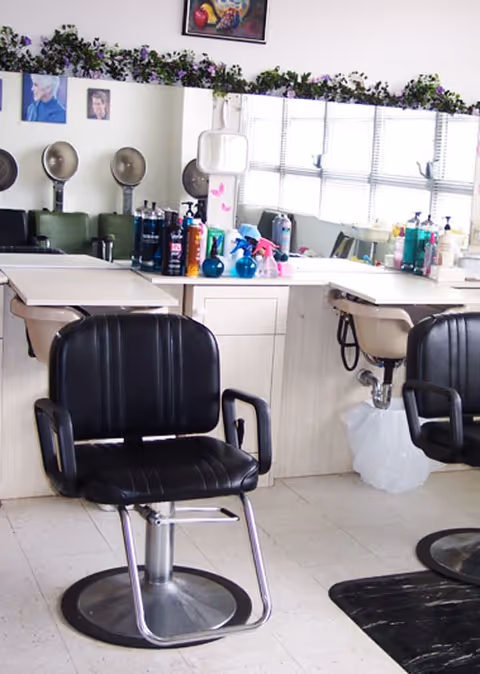 Interior hair salon in a senior living facility with chairs, mirrors, and hair products.
