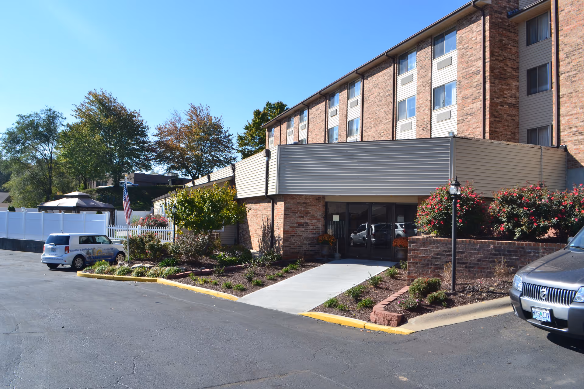 Brick senior living building exterior with entrance canopy, parking lot, and landscaping.