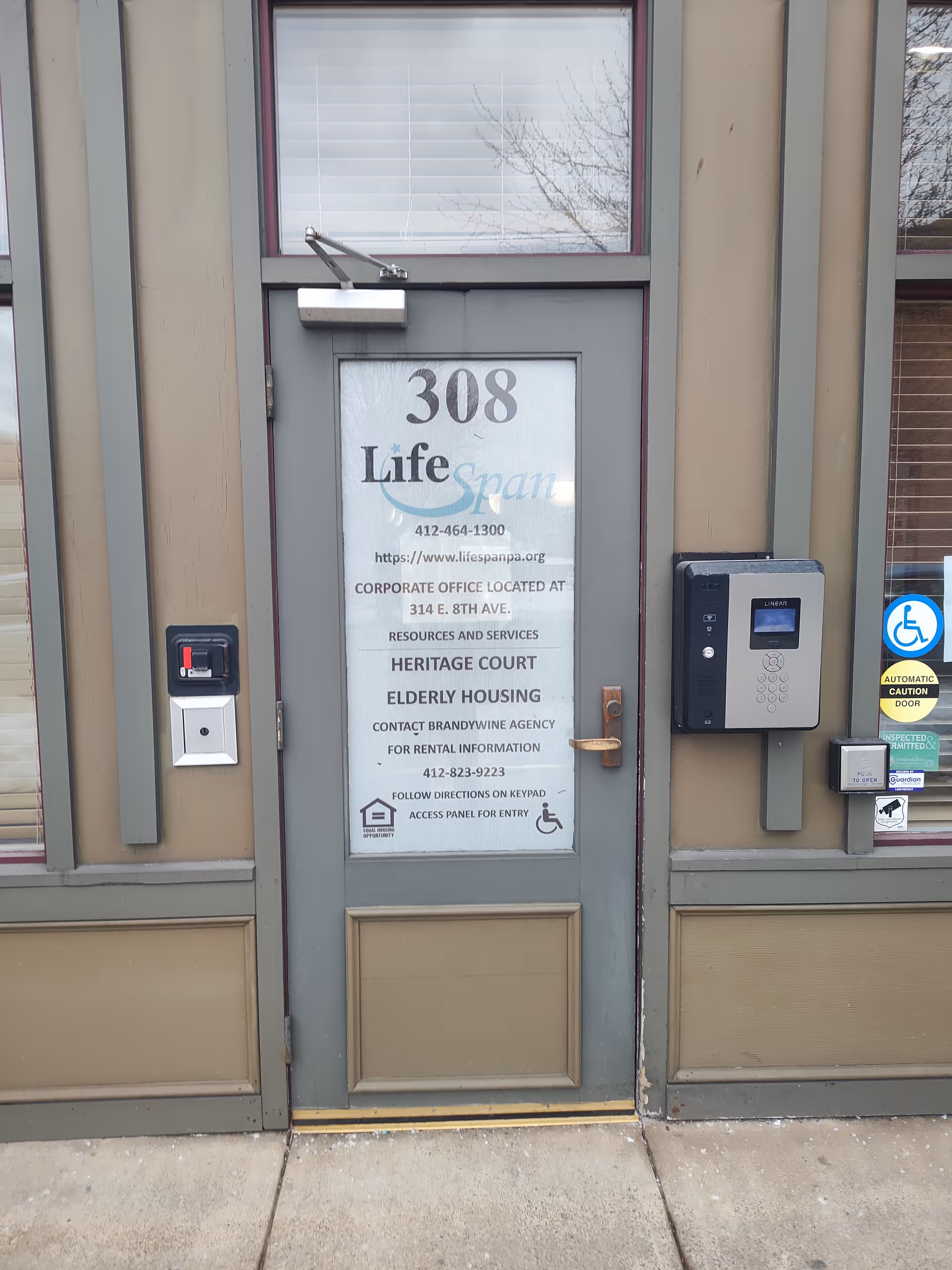 Exterior front door of a senior housing building with 308 Life signage and accessibility features.