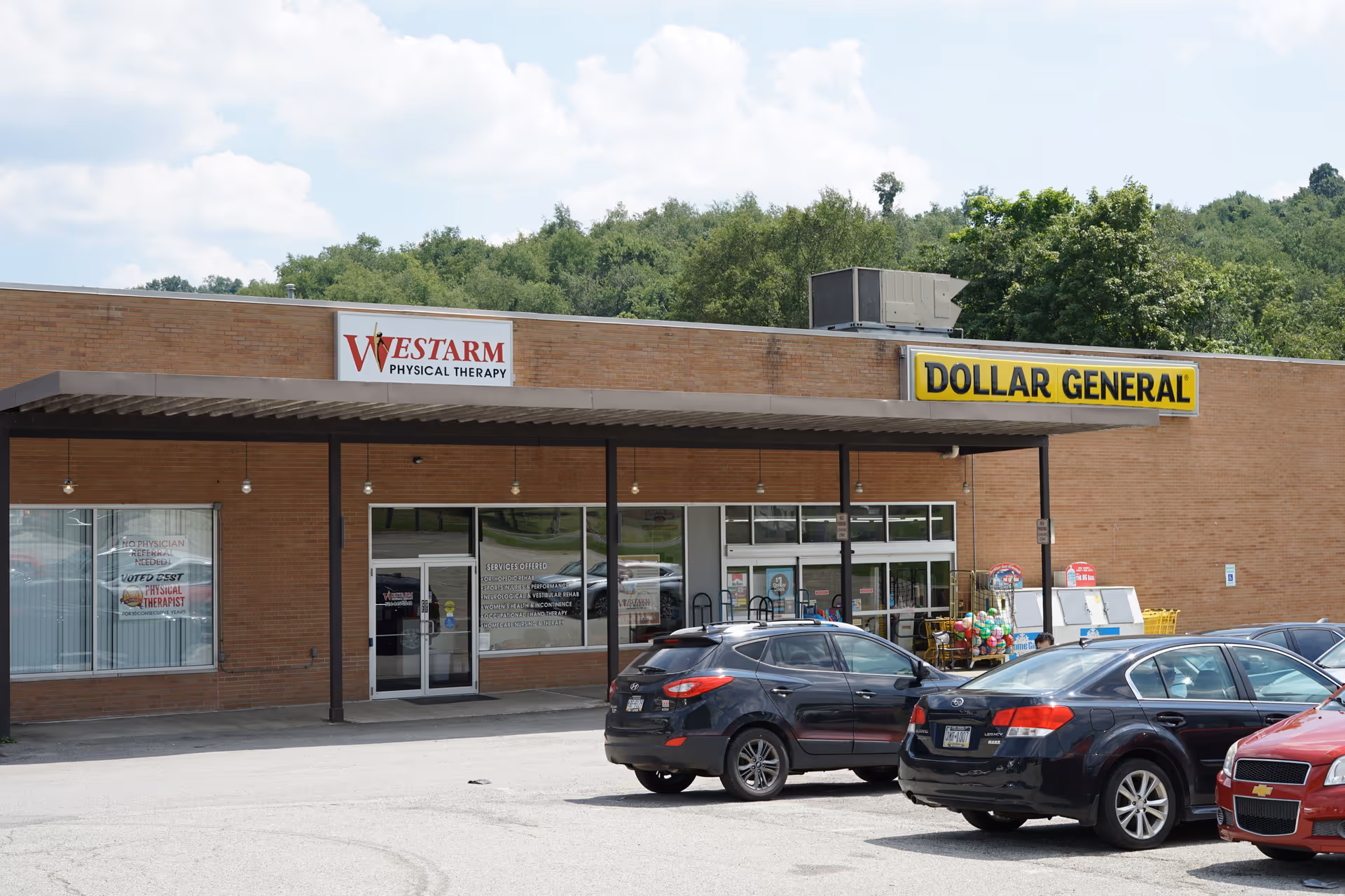Brick storefronts show WESTARM Physical Therapy Leechburg and Dollar General with parked cars.