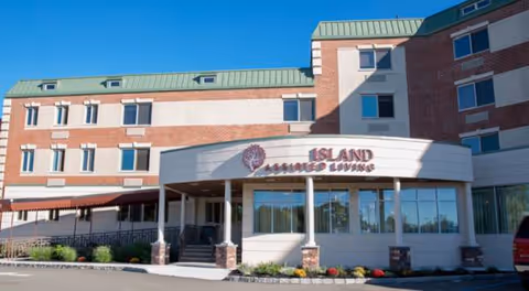 Exterior view of Island Assisted Living facility with glass entry and brick facade.