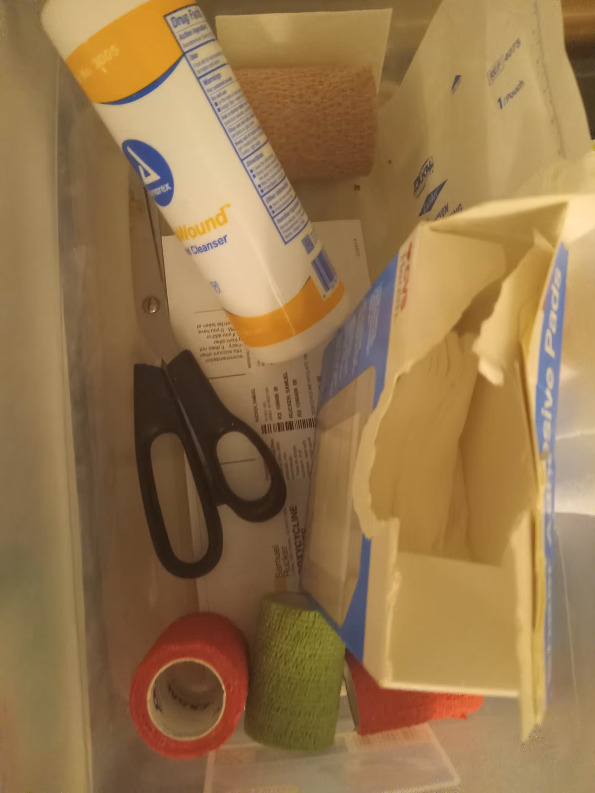 Close-up of a medical supply drawer with scissors, tape, gauze, and packaging.