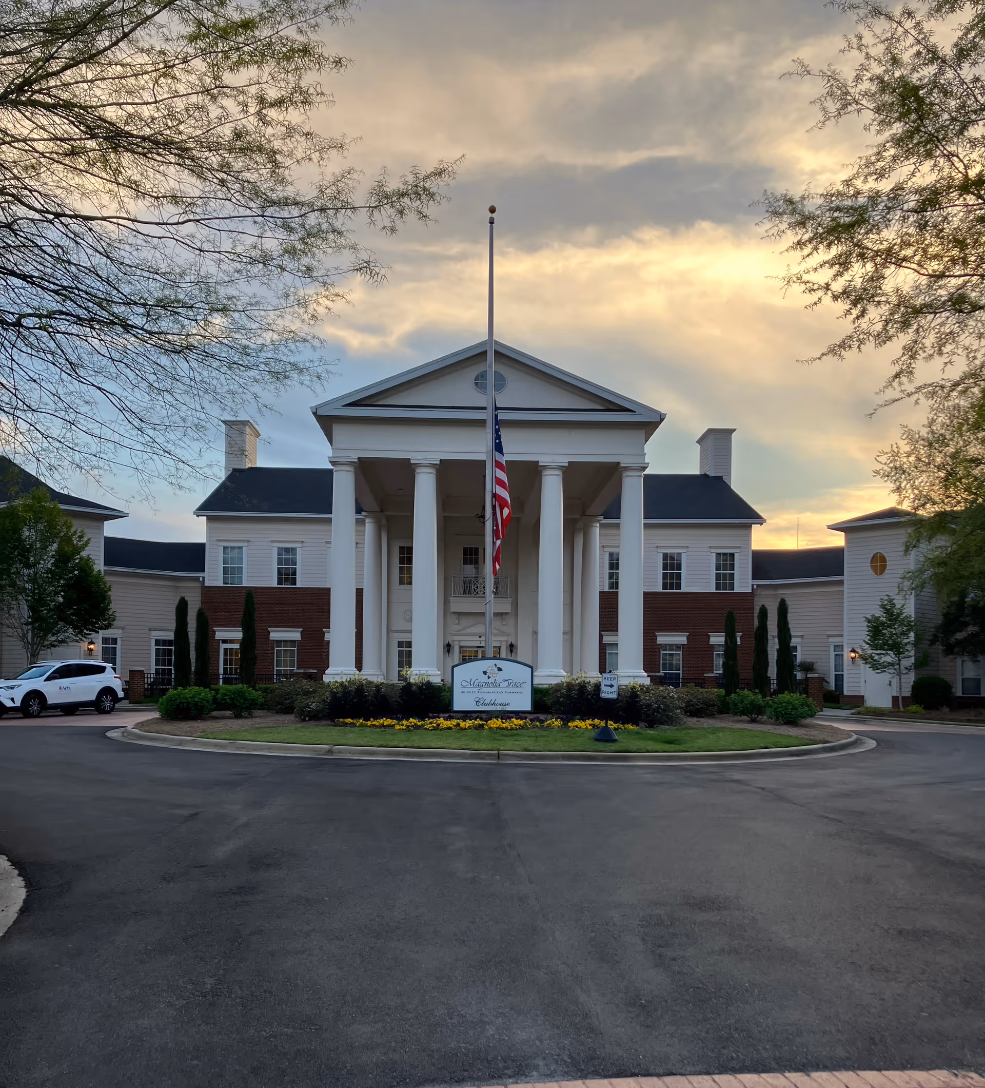 Exterior view of a neoclassical retirement community building with a flagpole
