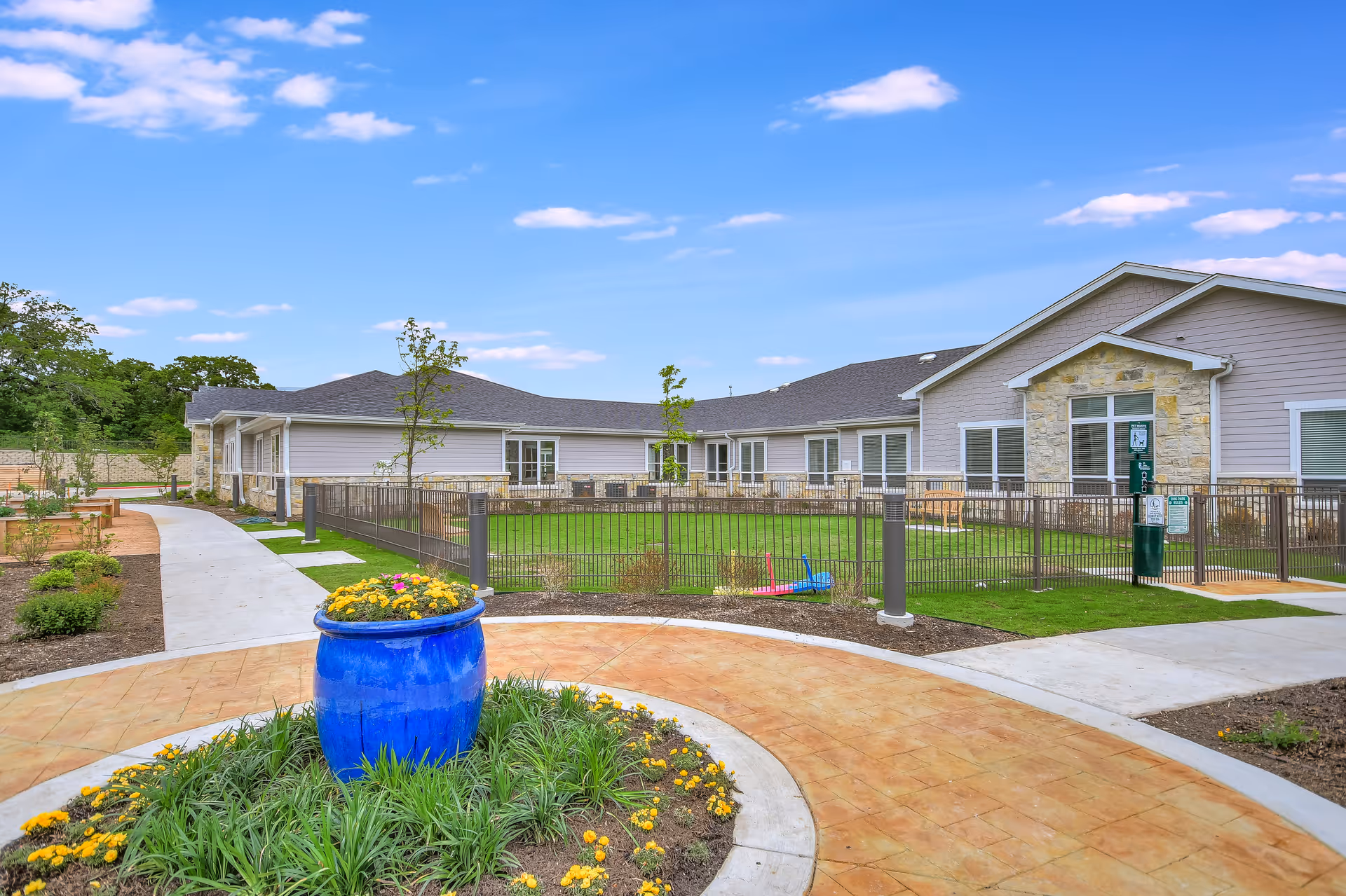 Exterior view of Legacy Oaks of Azle Senior Living with curved walkway and blue planter.