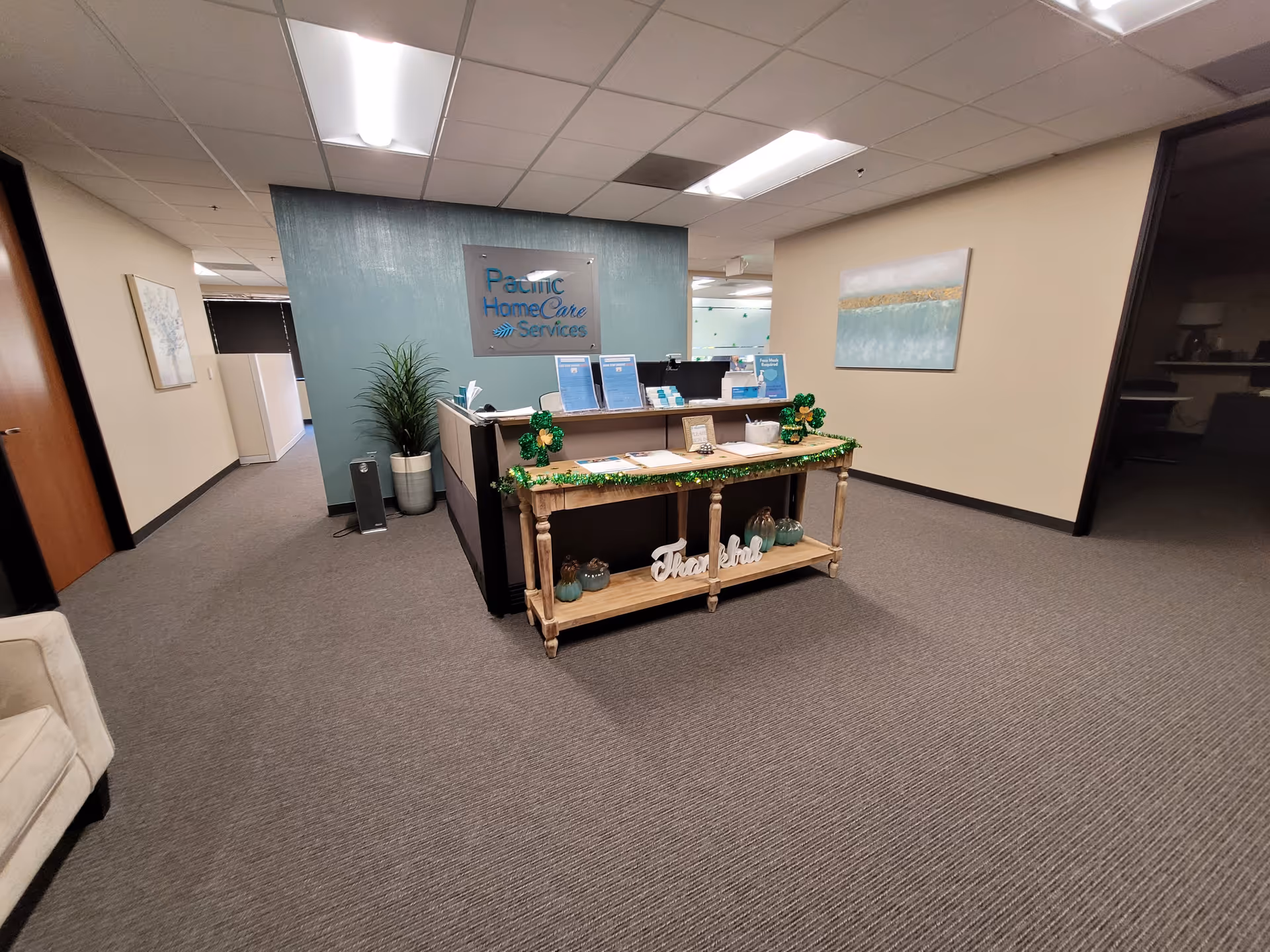 Reception desk in Pacific HomeCare Services lobby with teal wall and decor.