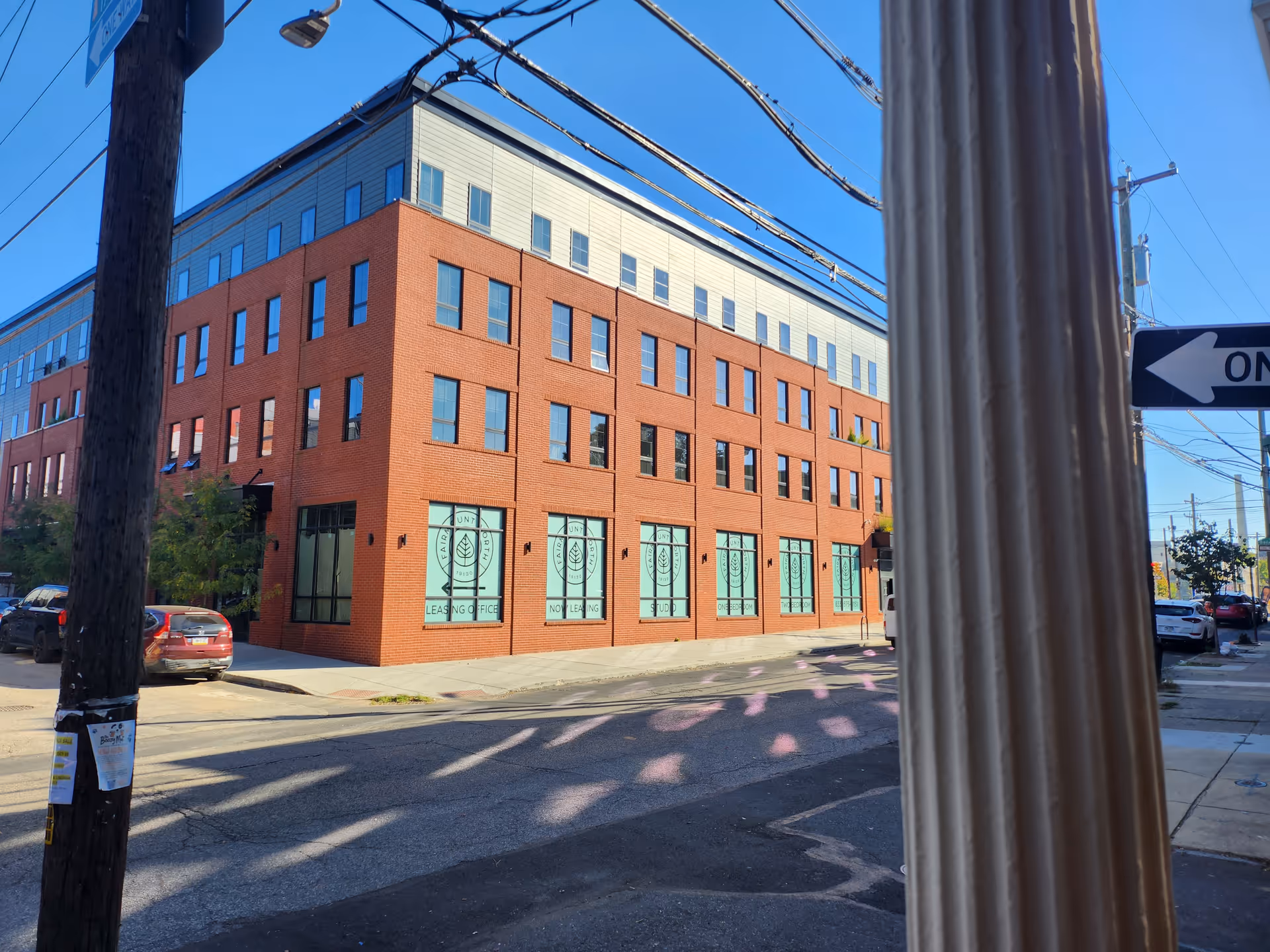 Brick multi-story building on a street corner with large storefront windows.