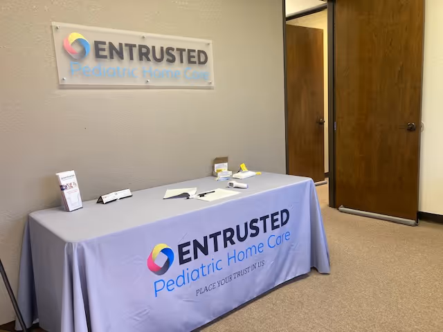 Table with Entrusted Pediatric Home Care branding sits in an interior hallway.