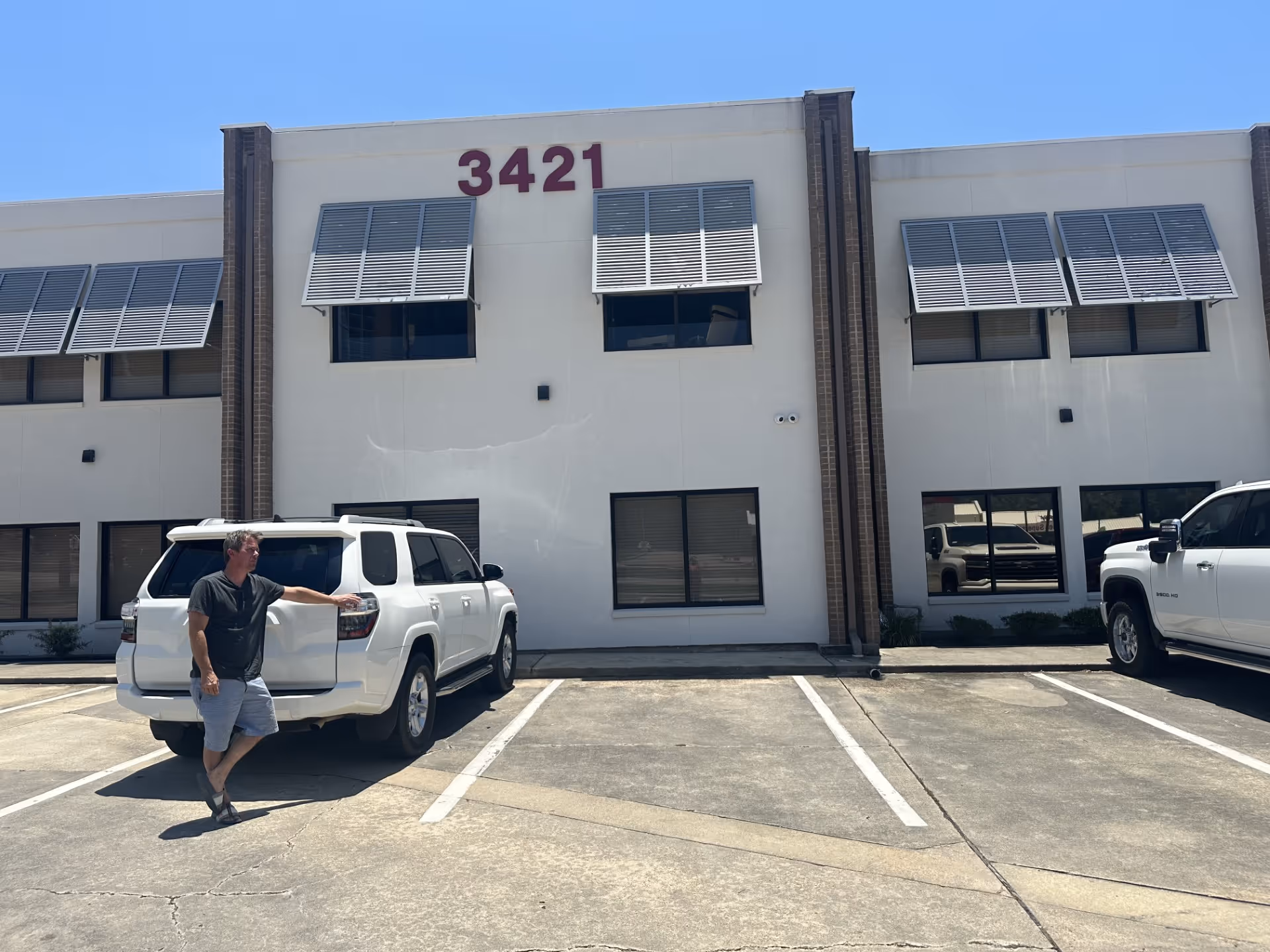 Front facade of a two-story facility with the number 3421 and parked vehicles.