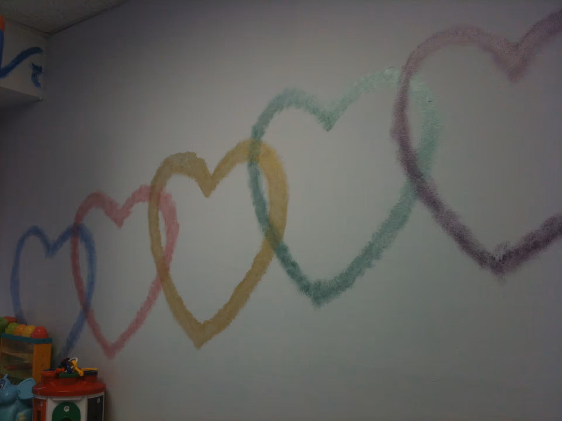 Interior playroom with colorful heart mural and assorted toy playthings.