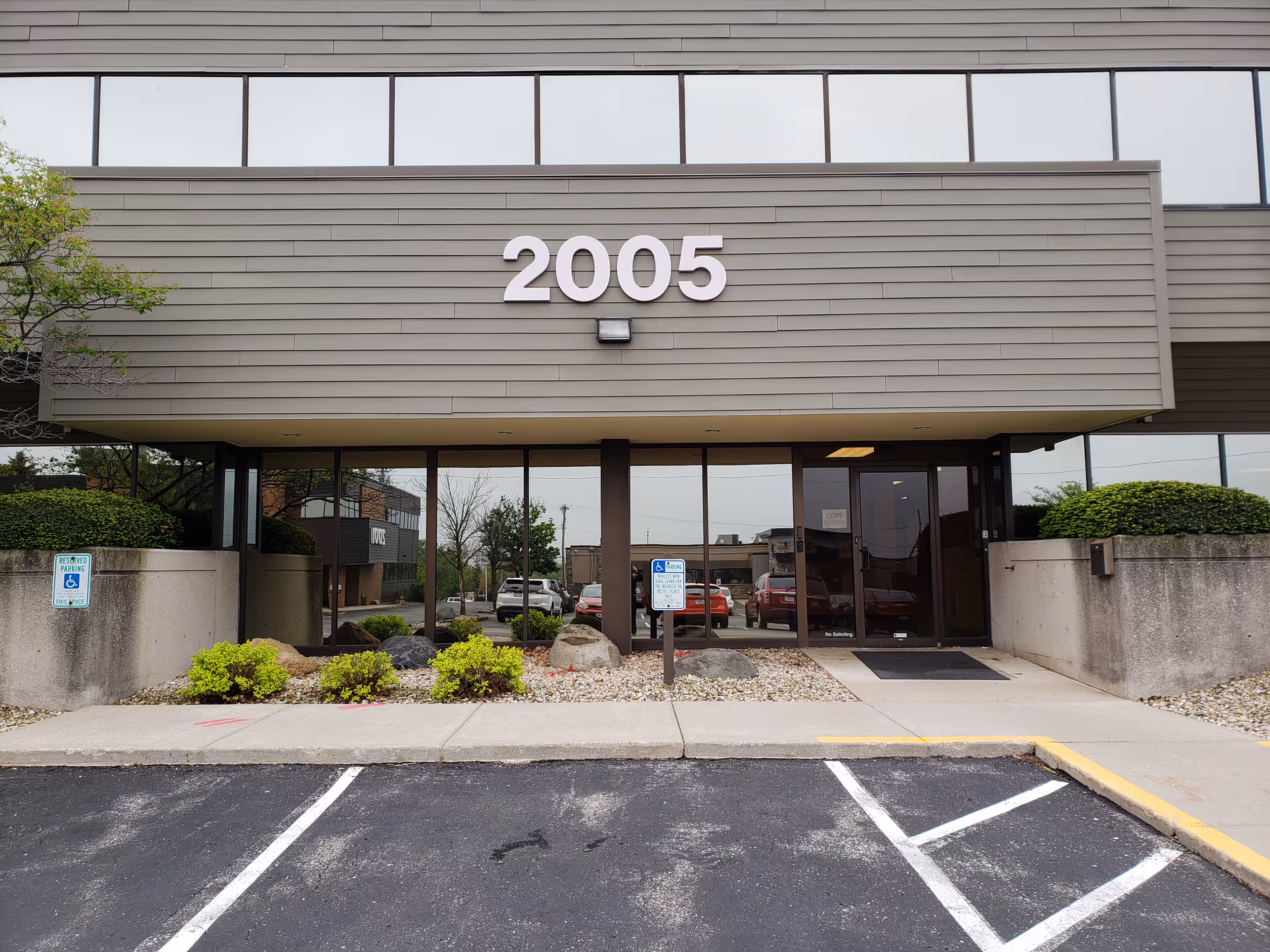 Front exterior of REM Wisconsin building with large 2005 number and glass entrance doors.