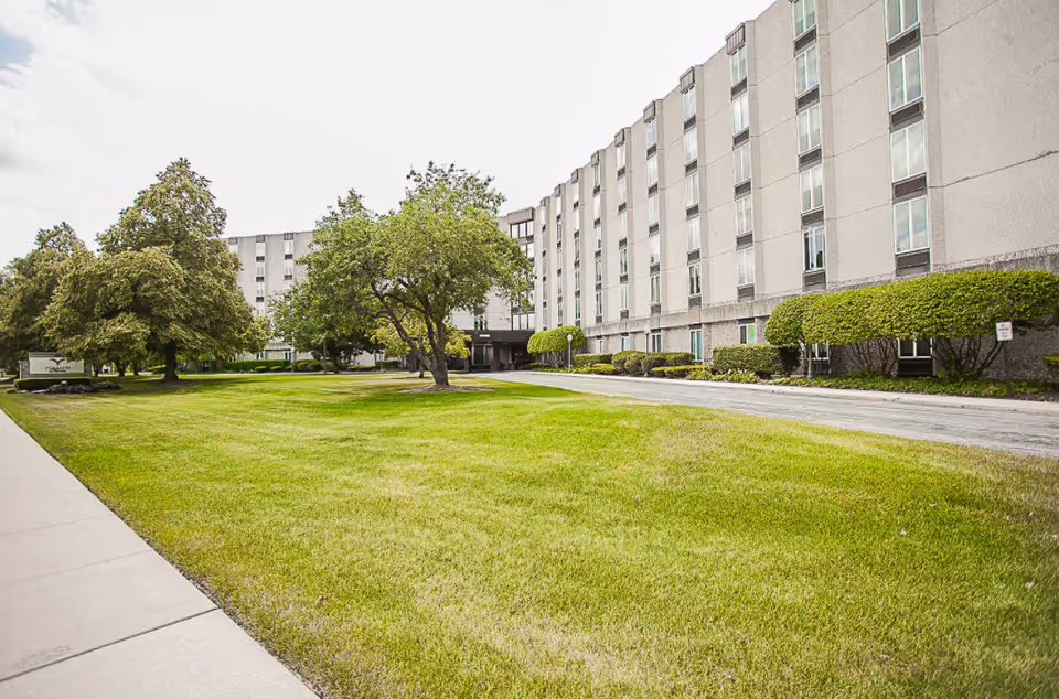 Wide exterior view of a multi-story senior living building with green lawn.