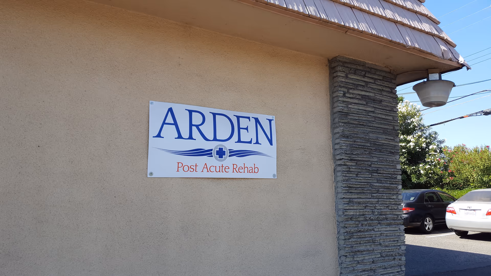 Exterior wall of Arden Post Acute Rehab building with a blue-and-white sign