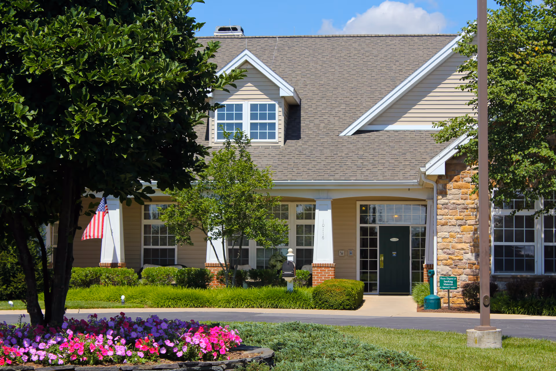 Front view of Somerford House Hagerstown entrance surrounded by trees, flowers, and a flag.
