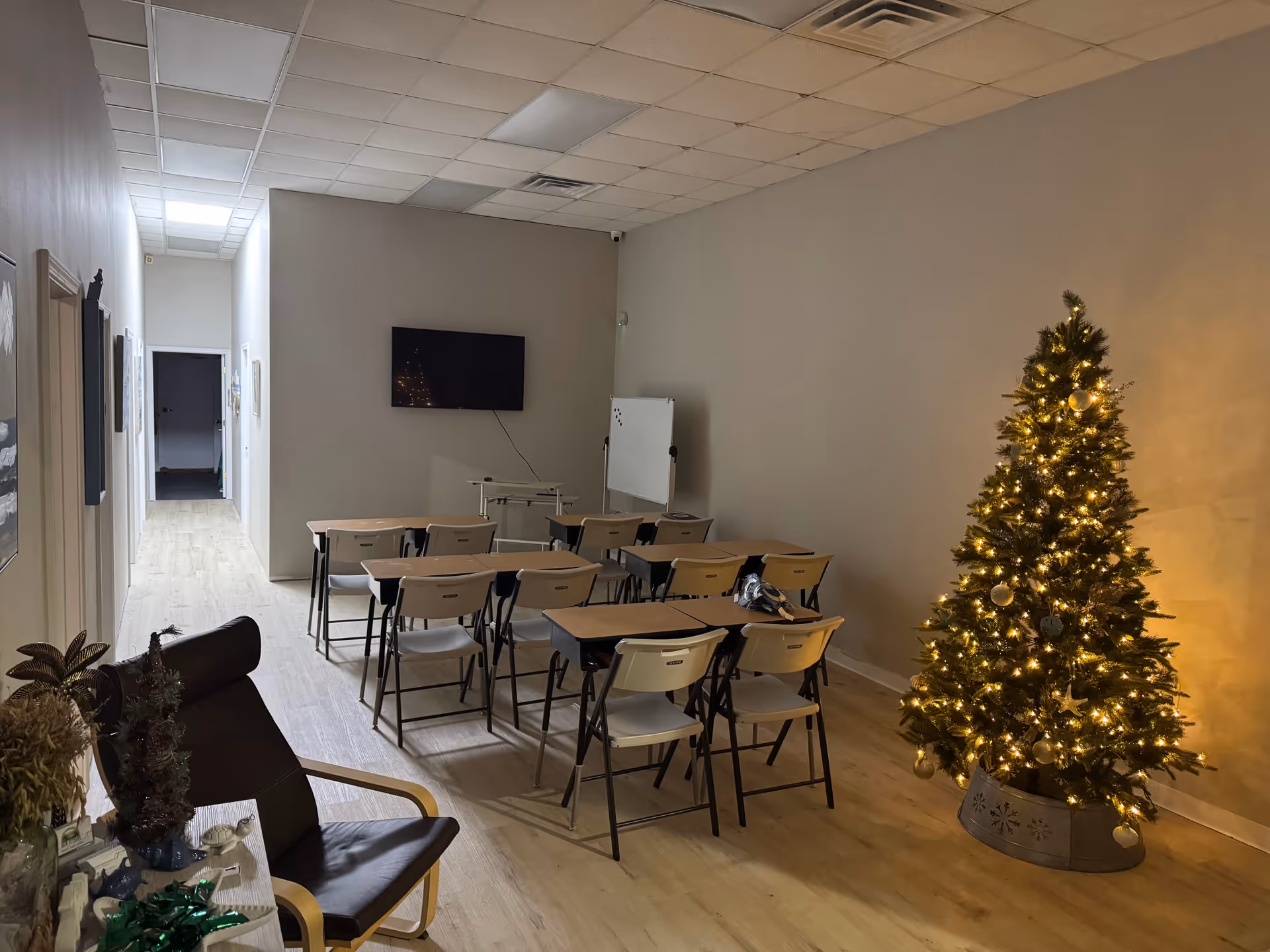 A classroom-like activity room with folding chairs, a Christmas tree, and a wall-mounted TV.