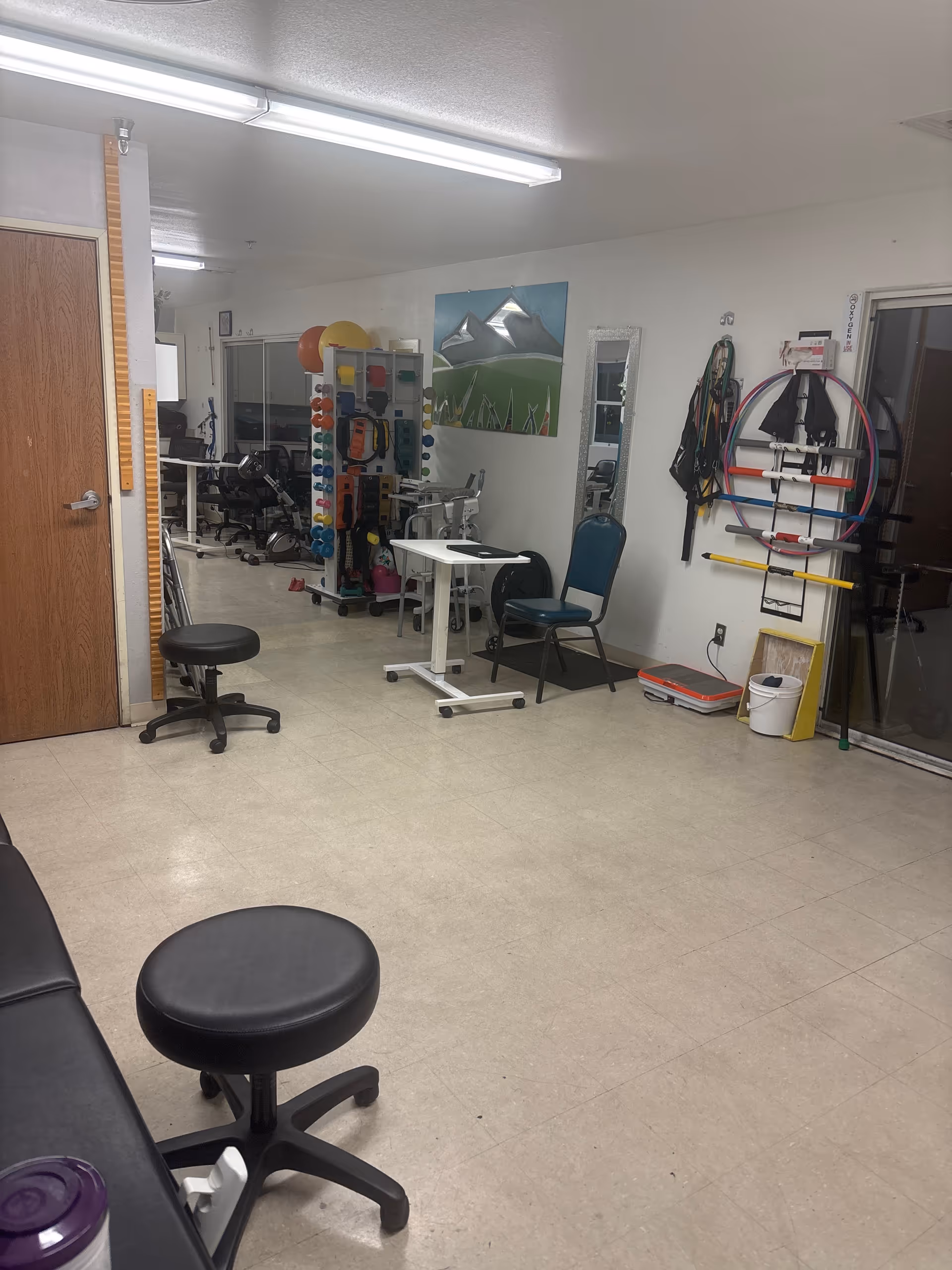 Senior living facility rehabilitation gym with exercise equipment and seating.