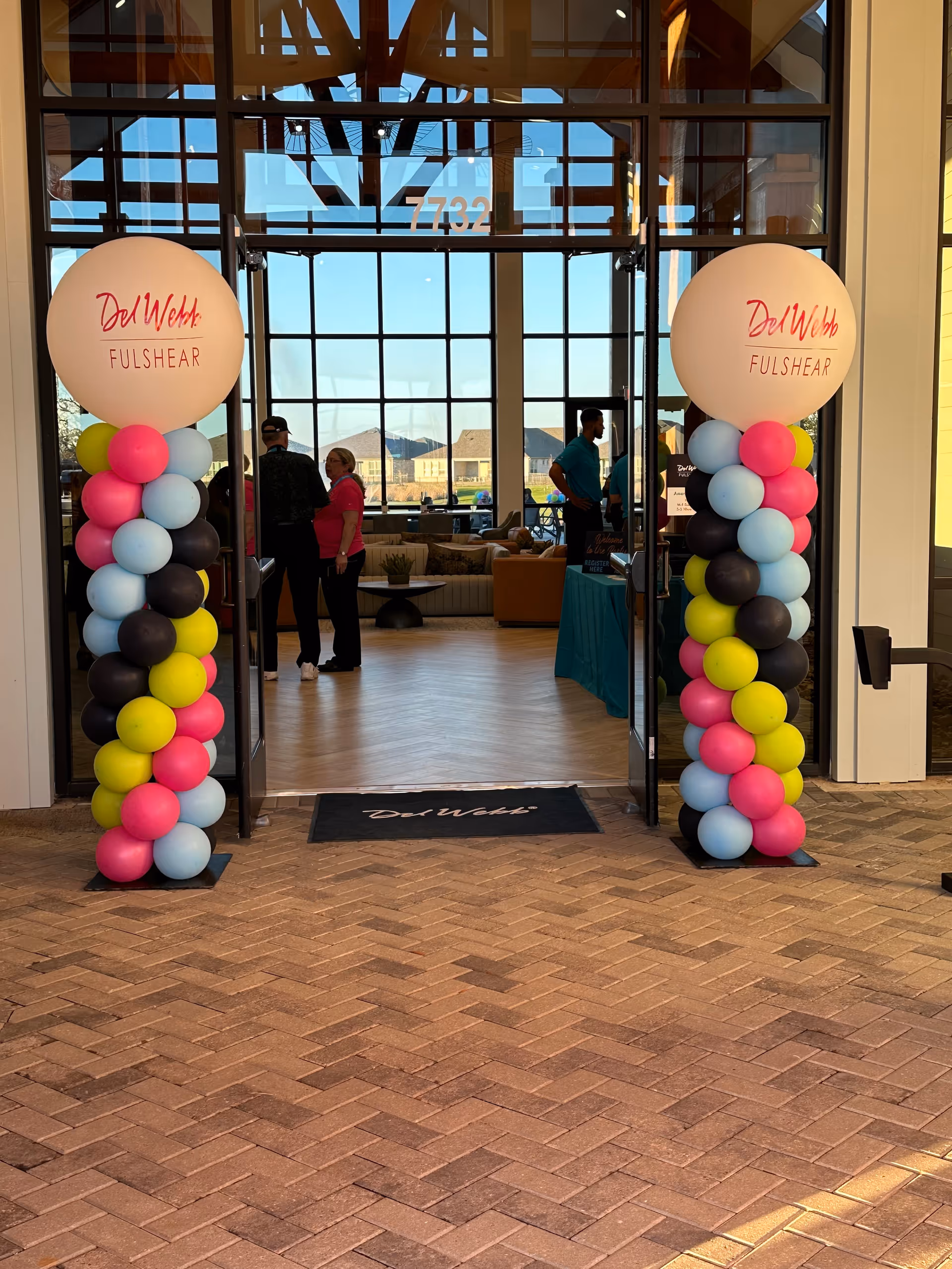 Entrance to Nurse Next Door Katy with balloon arches and people inside.