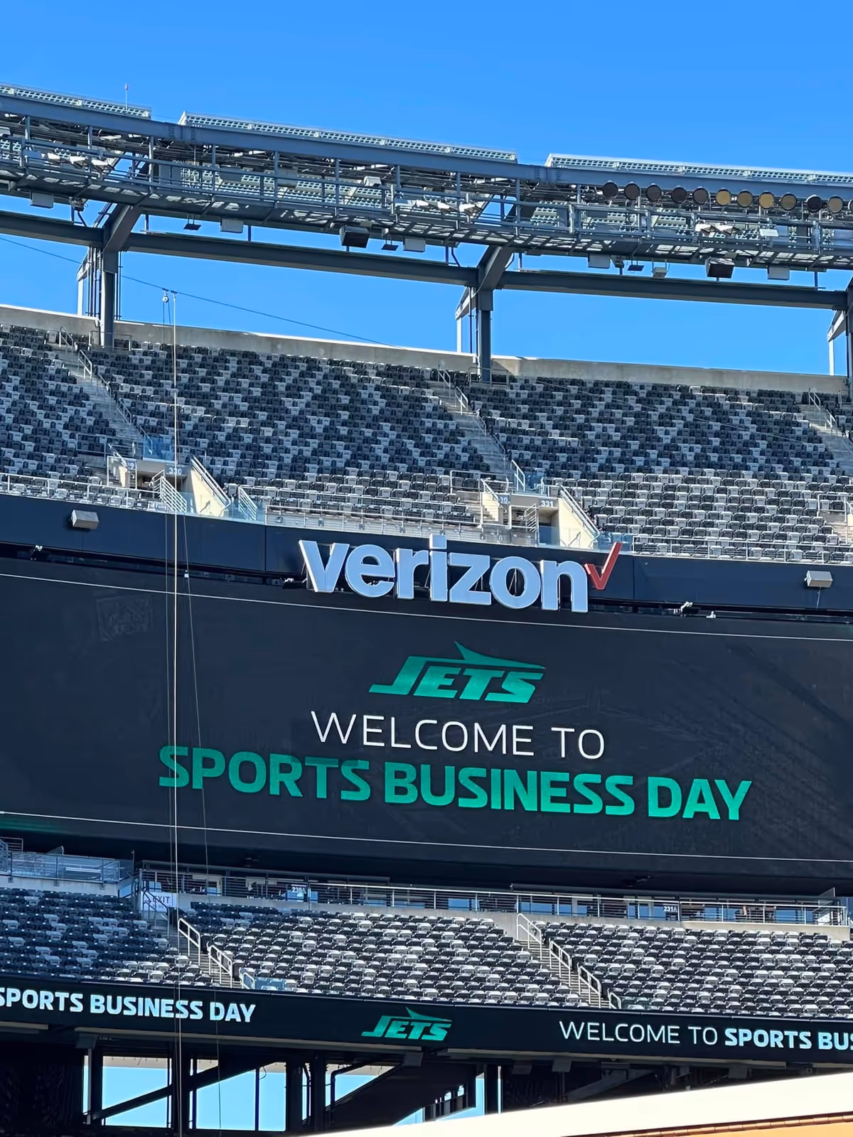 Exterior view of a stadium with Verizon and Jets branding on a large screen.