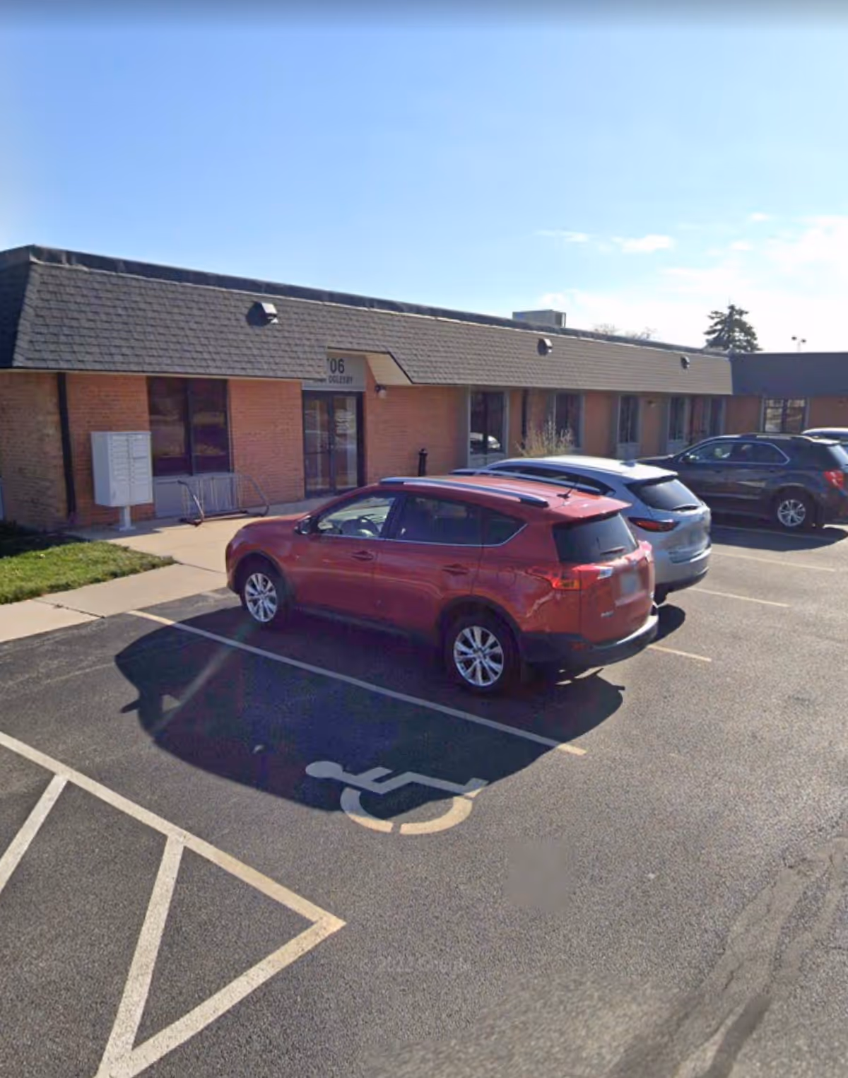 Single-story brick facility façade with a parking lot and accessible handicap space.