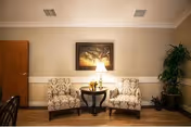 Two patterned armchairs flank a small table with a lamp in a cozy living area.